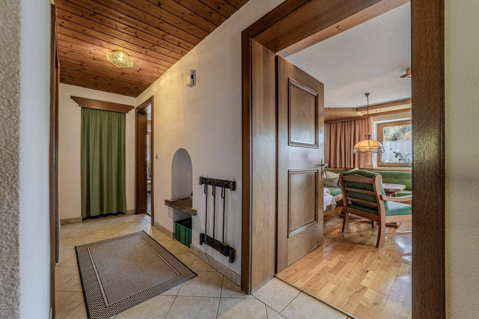 Eingangsbereich mit Fliesenboden, Holzdecke und Zugang zu verschiedenen Räumen.