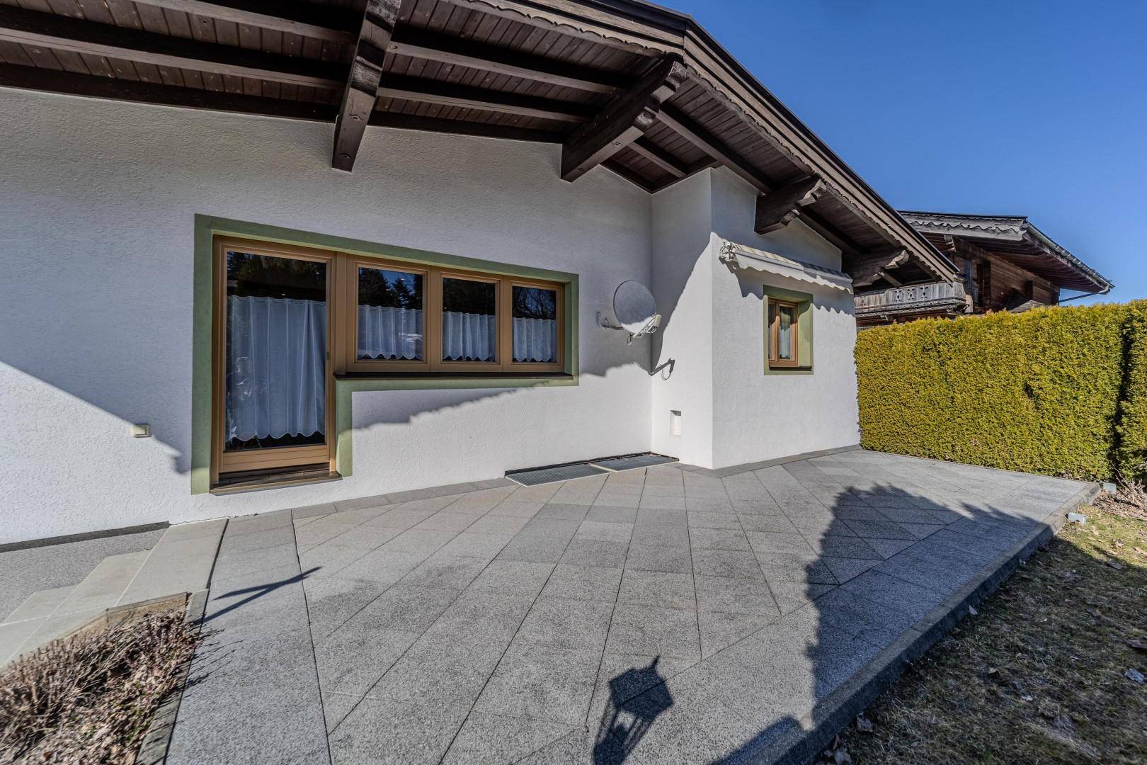 Gepflasterte Terrasse am Haus mit direktem Zugang zum Garten und Blick auf die Umgebung.