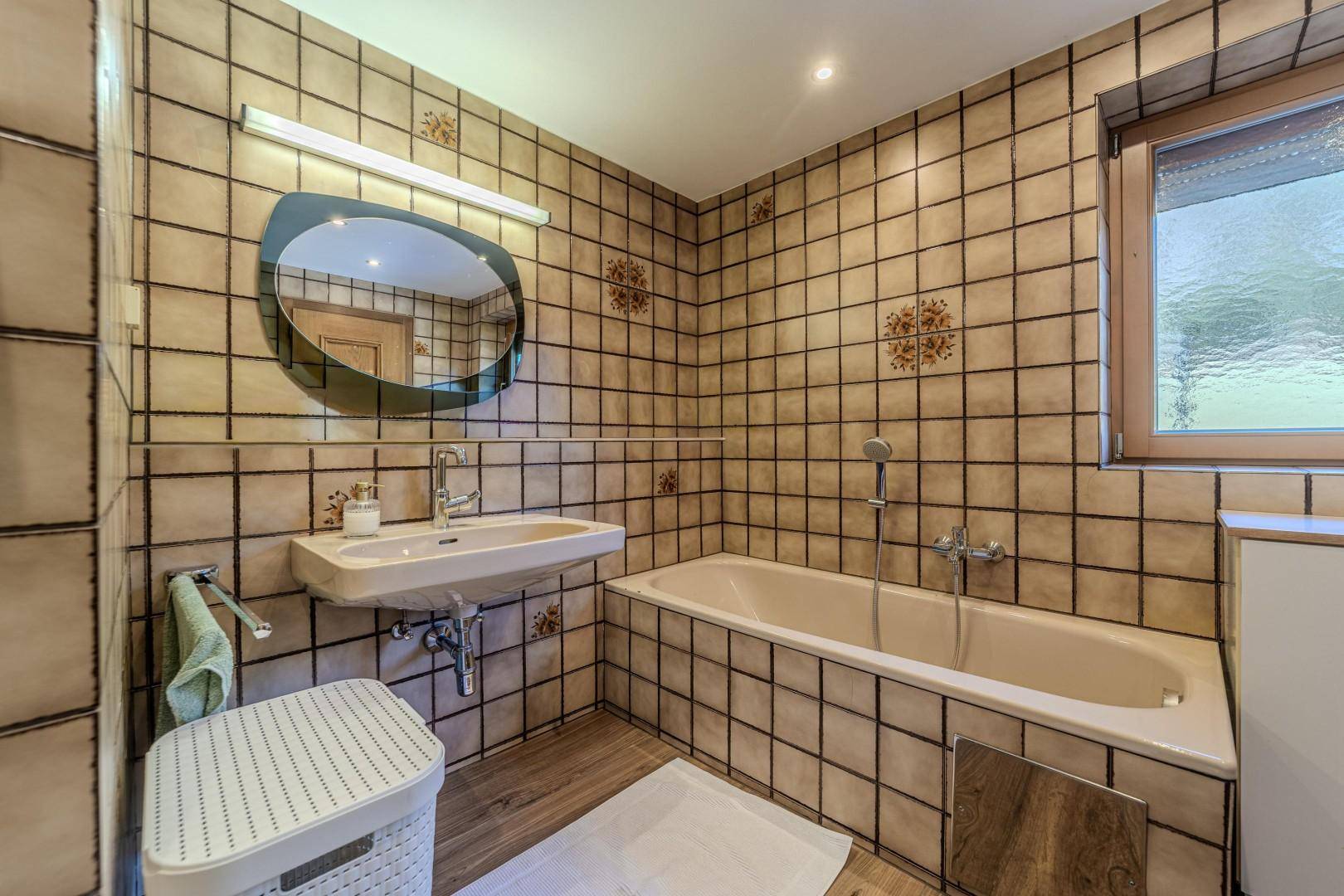 Badezimmer mit Badewanne, Waschbecken und Fenster für natürliche Belüftung.