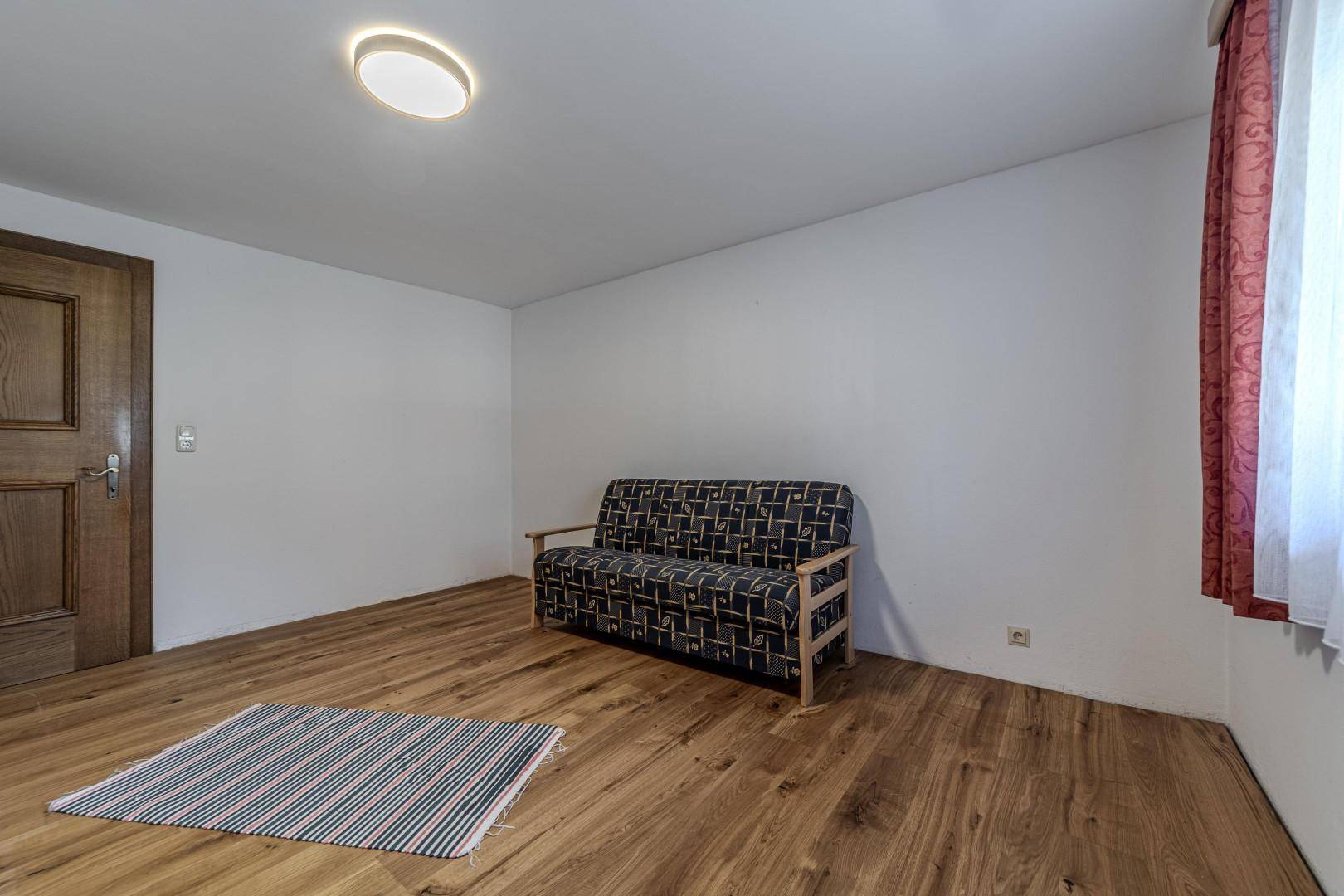 Helles Zimmer mit Holzboden und schlichter Gestaltung, bietet Raum für individuelle Einrichtung.
