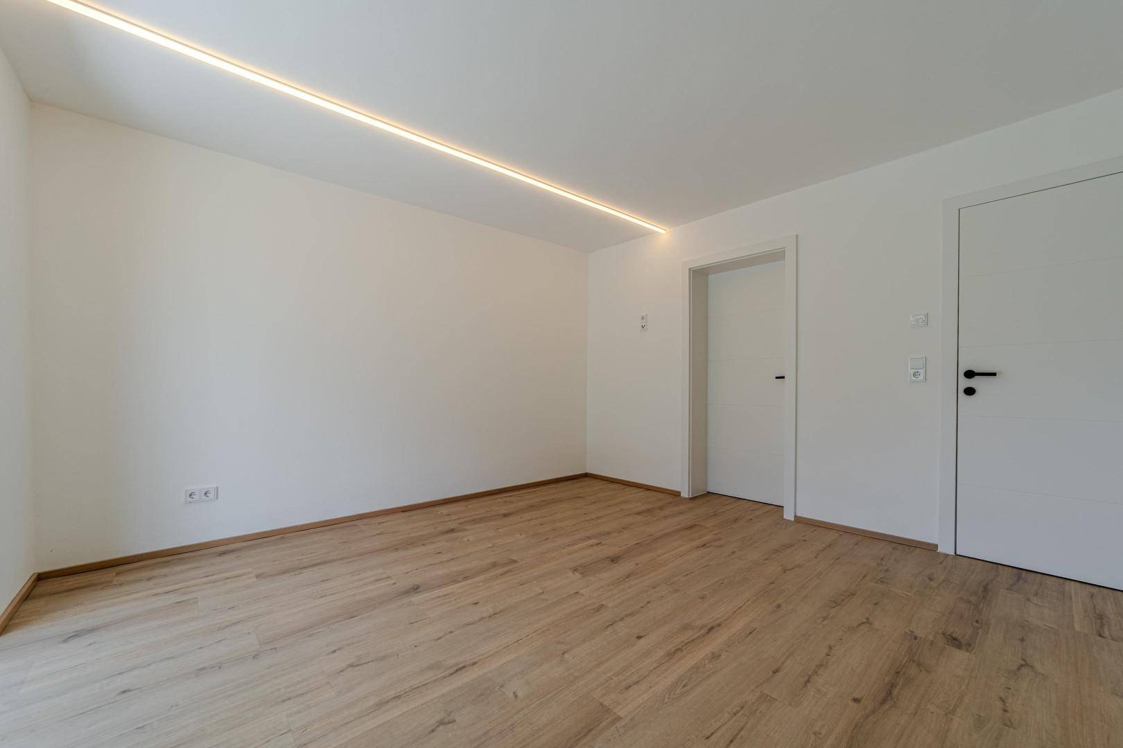 Schlichter Raum mit Holzboden und zwei weißen Türen, ideal für verschiedene Nutzungen.