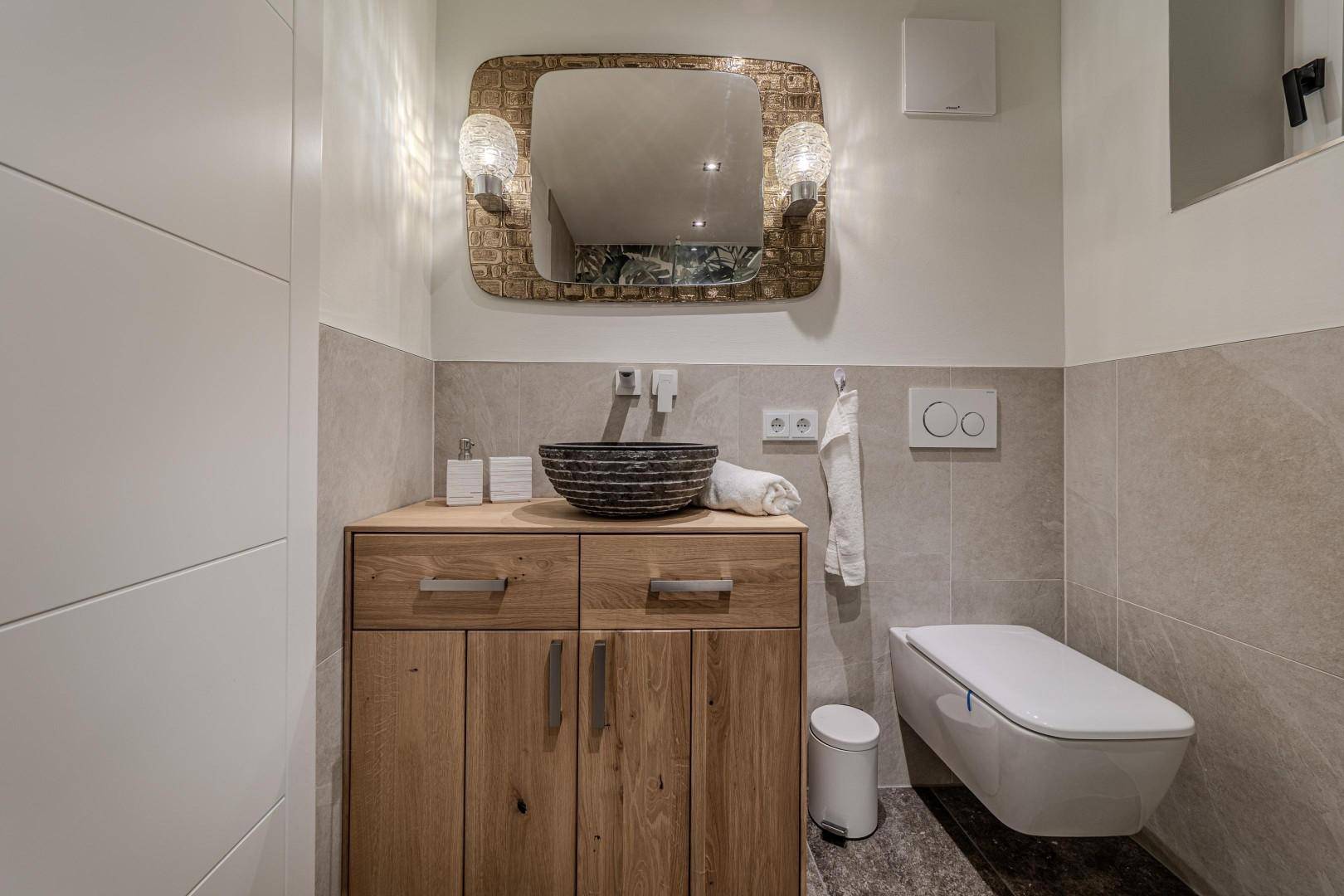 Modernes Gäste-WC mit Holzwaschtisch, Wand-WC und stilvollen Fliesen.