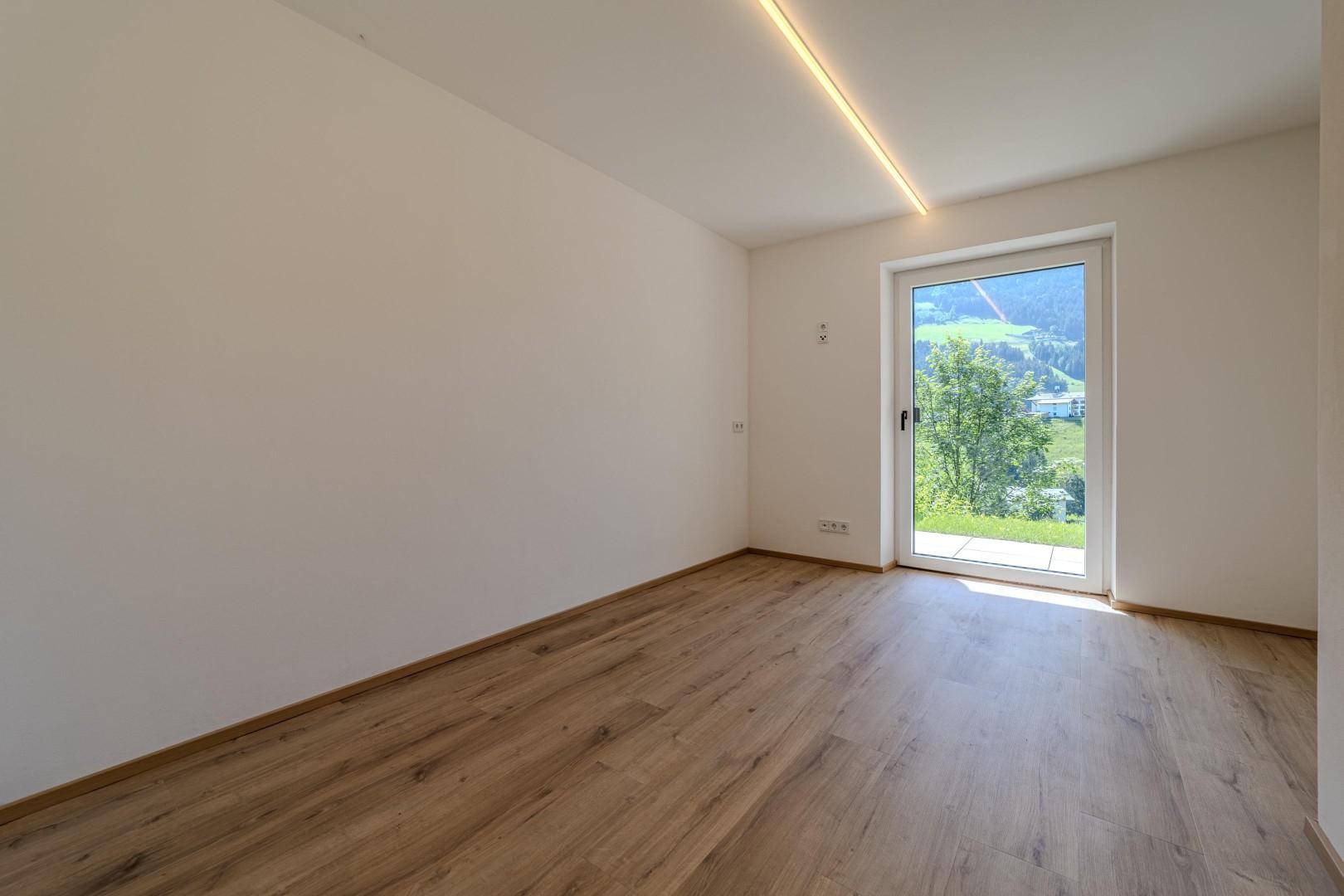 Geräumiger, heller Raum mit Holzboden und Panoramablick auf die umliegende Berglandschaft.