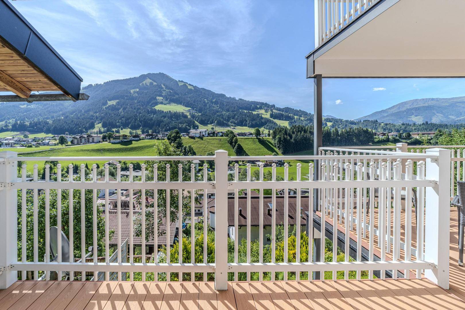 Balkon mit weißem Geländer und weitem Blick auf die beeindruckende Berglandschaft unter blauem Himmel.