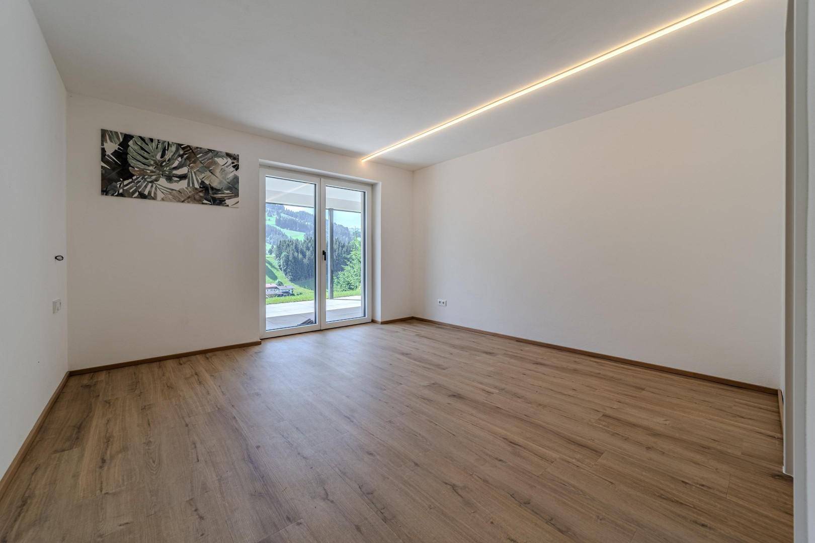 Heller Raum mit Schiebetür zum Außenbereich und Blick auf die grüne Berglandschaft.