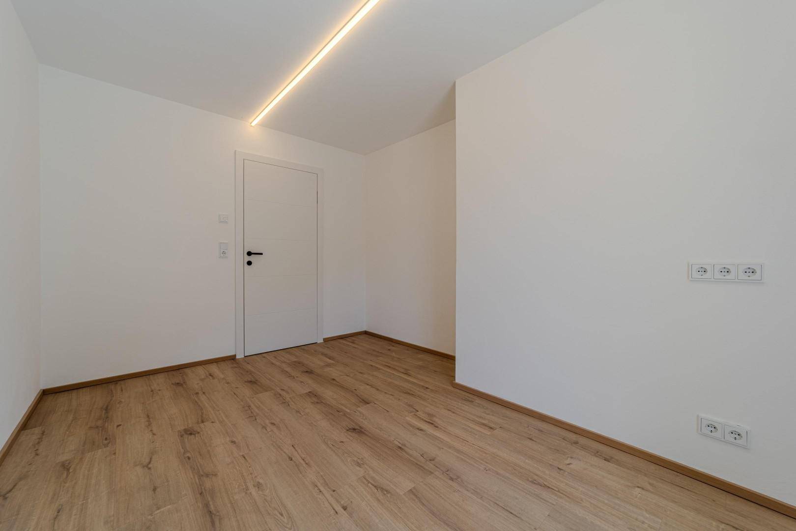 Leerer Raum mit Holzboden und weißer Tür, bereit für individuelle Gestaltung.