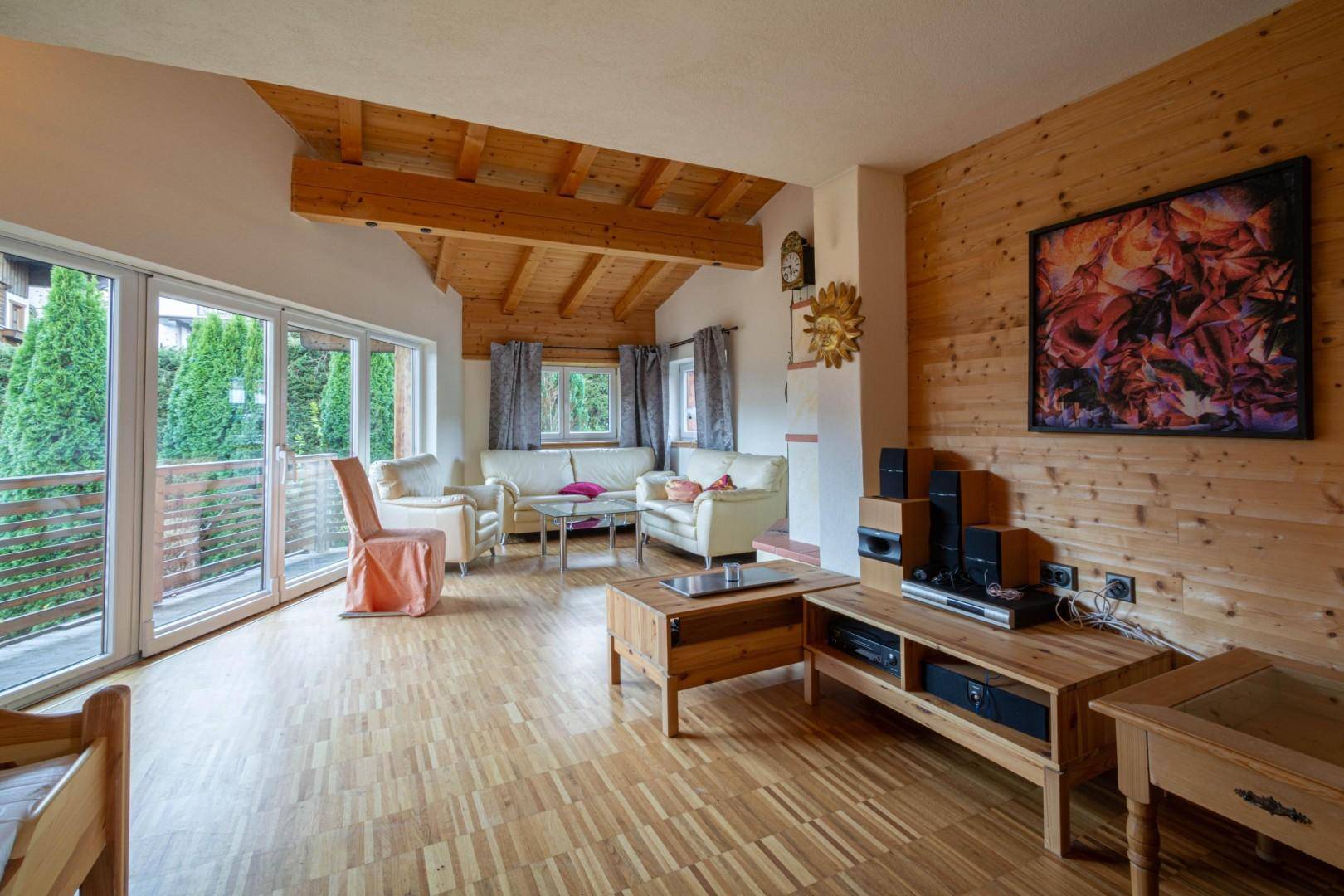 Geräumiges Wohnzimmer mit Holzbalkendecke, Kamin und Medienbereich, ideal zum Entspannen.
