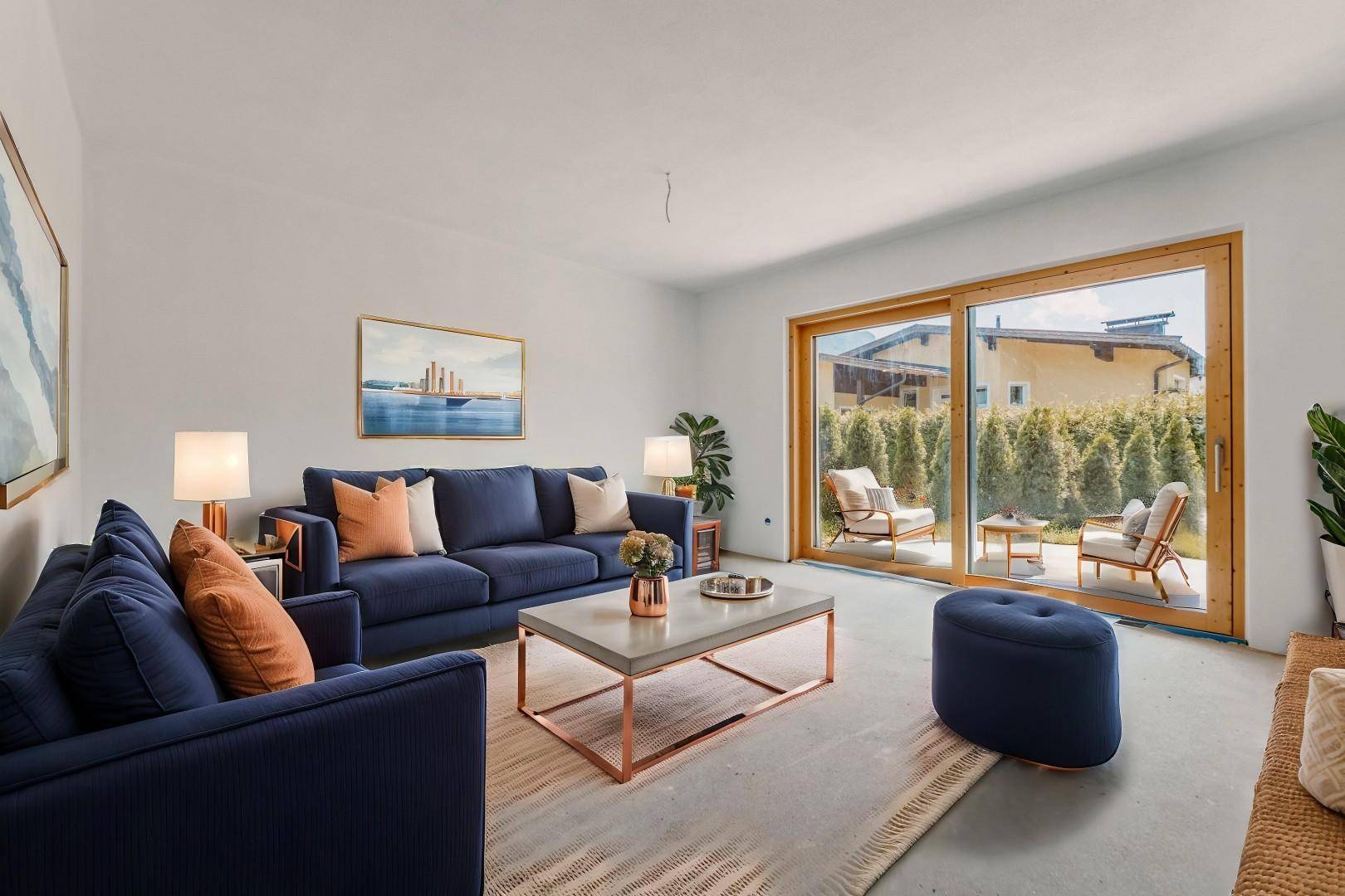 Geräumiges Wohnzimmer mit blauen Sofas, modernem Couchtisch und Blick auf die grüne Terrasse.