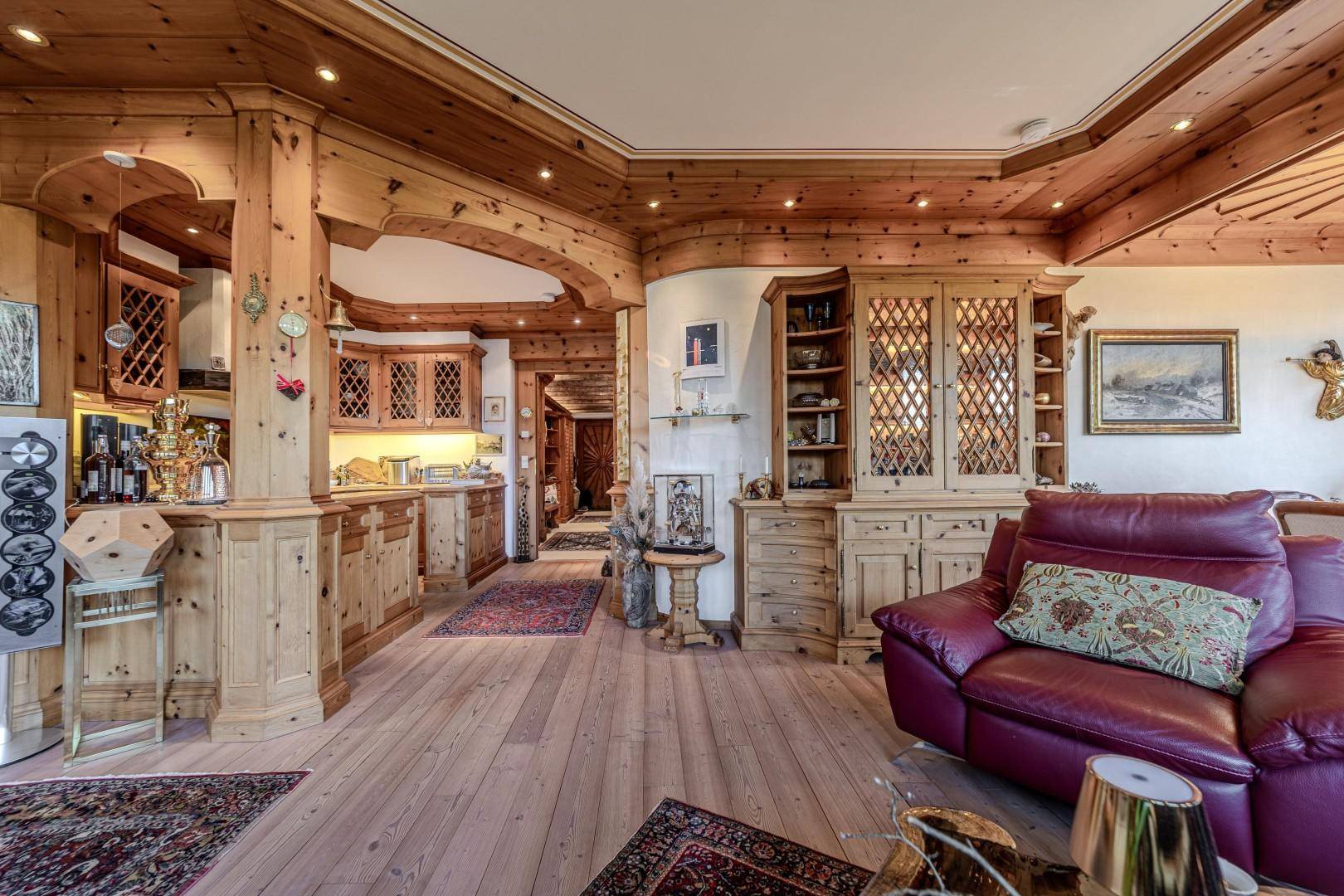Gemütlicher Wohnbereich mit Holzelementen, traditionellen Möbeln und Blick auf die offene Küche.