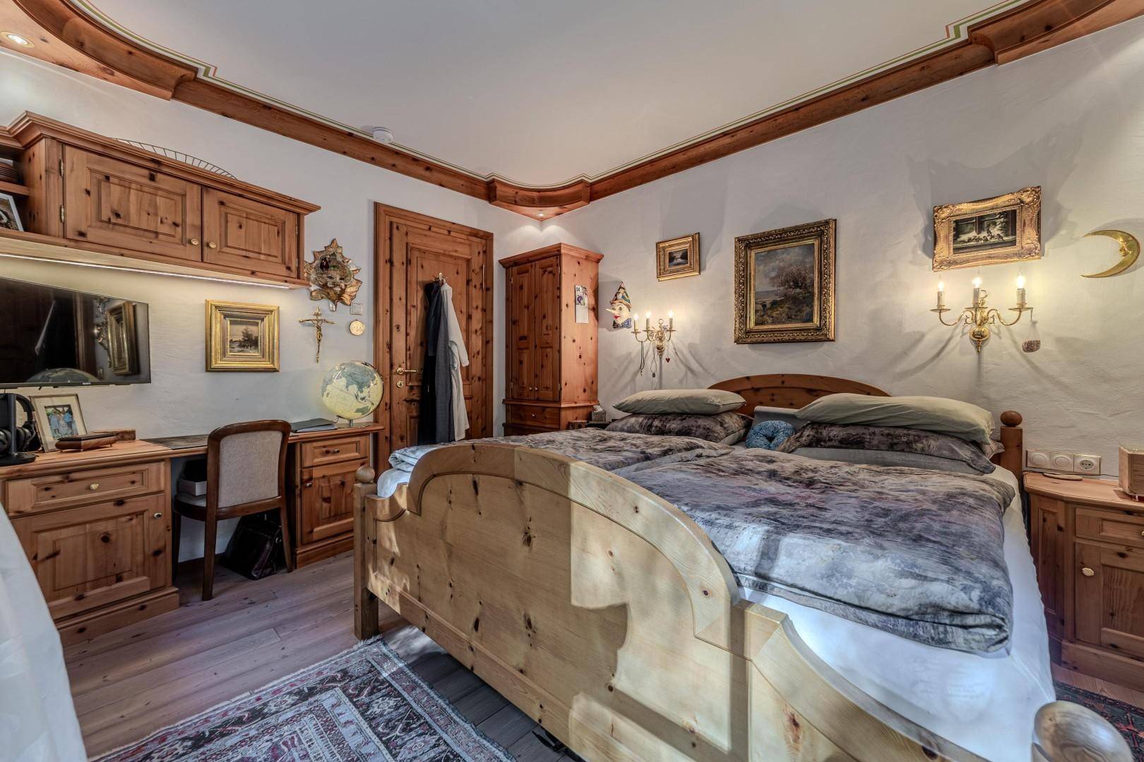 Schlafzimmer im Landhausstil mit Holzmöbeln, Doppelbett und traditioneller Dekoration.