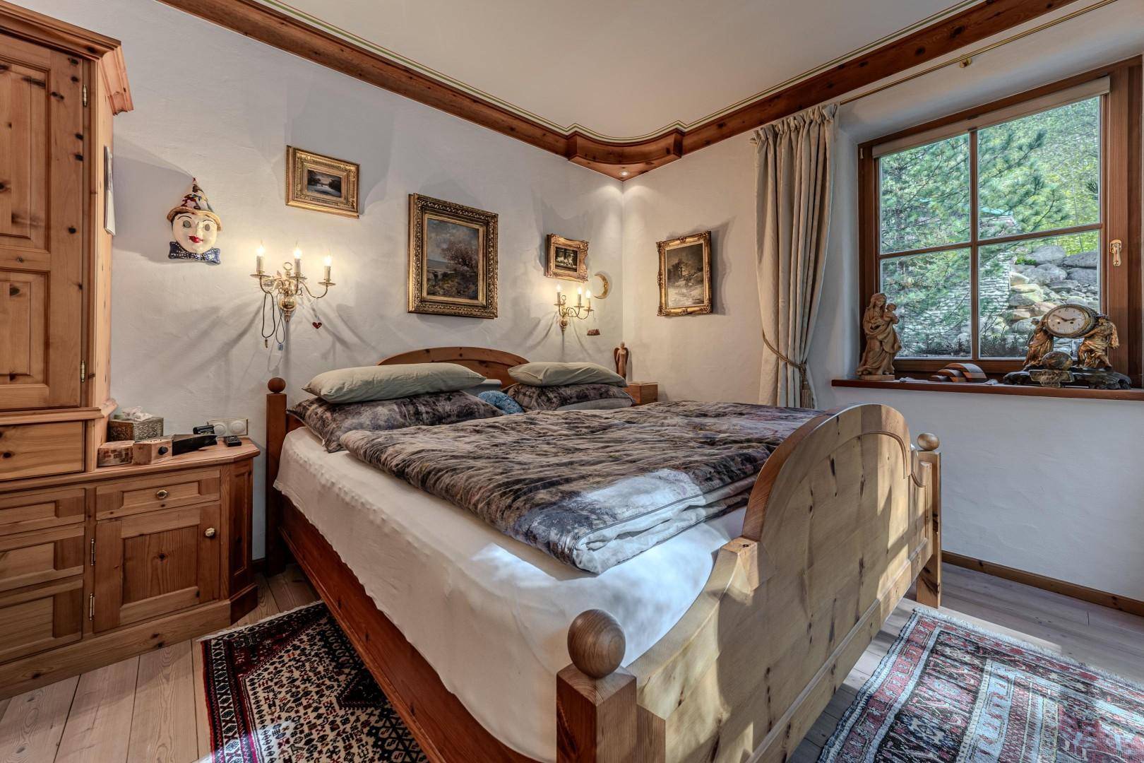 Gemütliches Schlafzimmer im alpinen Stil mit Holzbetten, Holzböden und Blick ins Grüne.