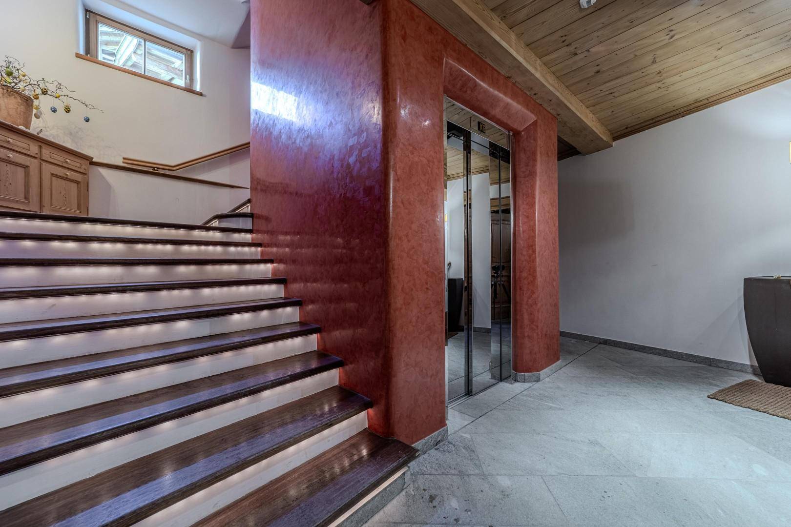 Elegantes Treppenhaus mit beleuchteten Stufen und einem modernen Aufzug für bequemen Zugang.