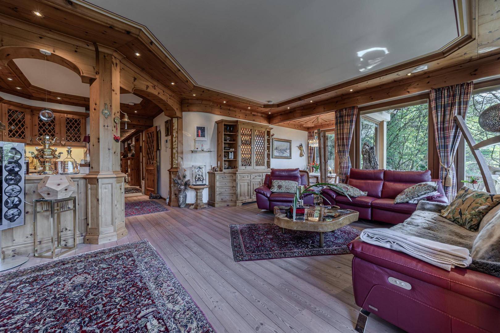 Offener Wohnbereich im alpinen Stil mit Holzböden, roten Ledersofas und angrenzender Küche.