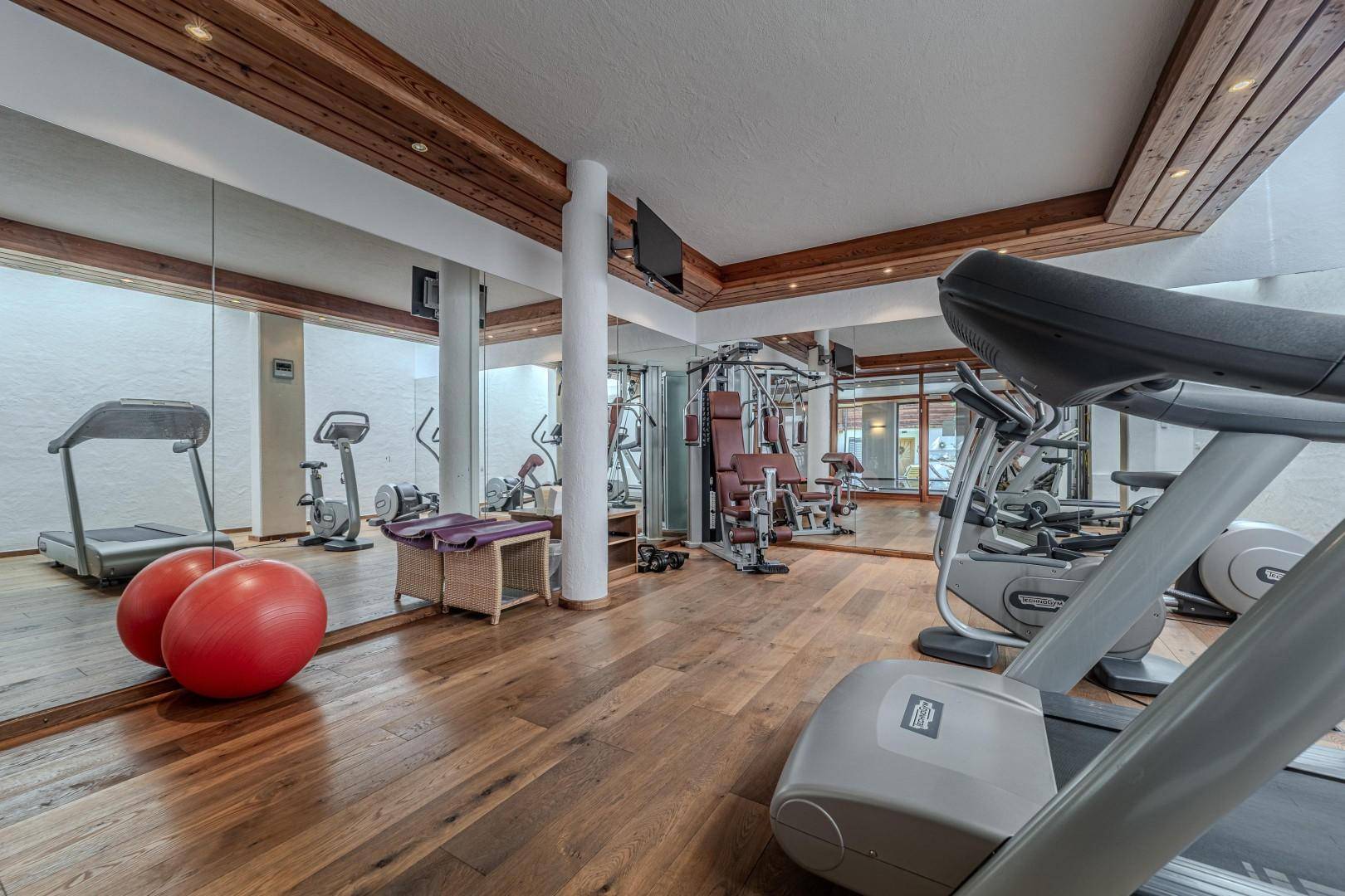 Gut ausgestatteter Fitnessraum mit Laufbändern, Fahrrädern und großen Spiegeln für das Training.