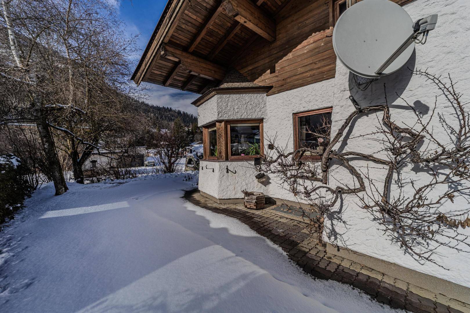 Fassade des Hauses im Winter mit Erkerfenster und Satellitenschüssel.