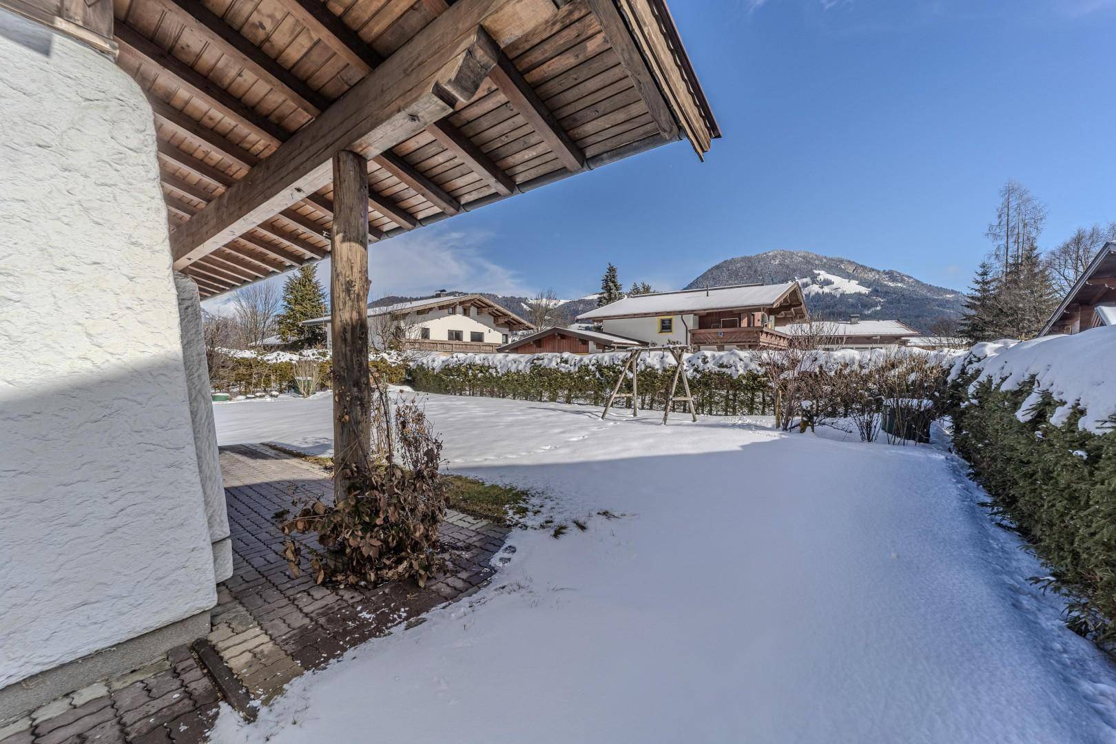 Verschneiter Gartenbereich mit Schaukelgestell und Blick auf die umliegende Berglandschaft.