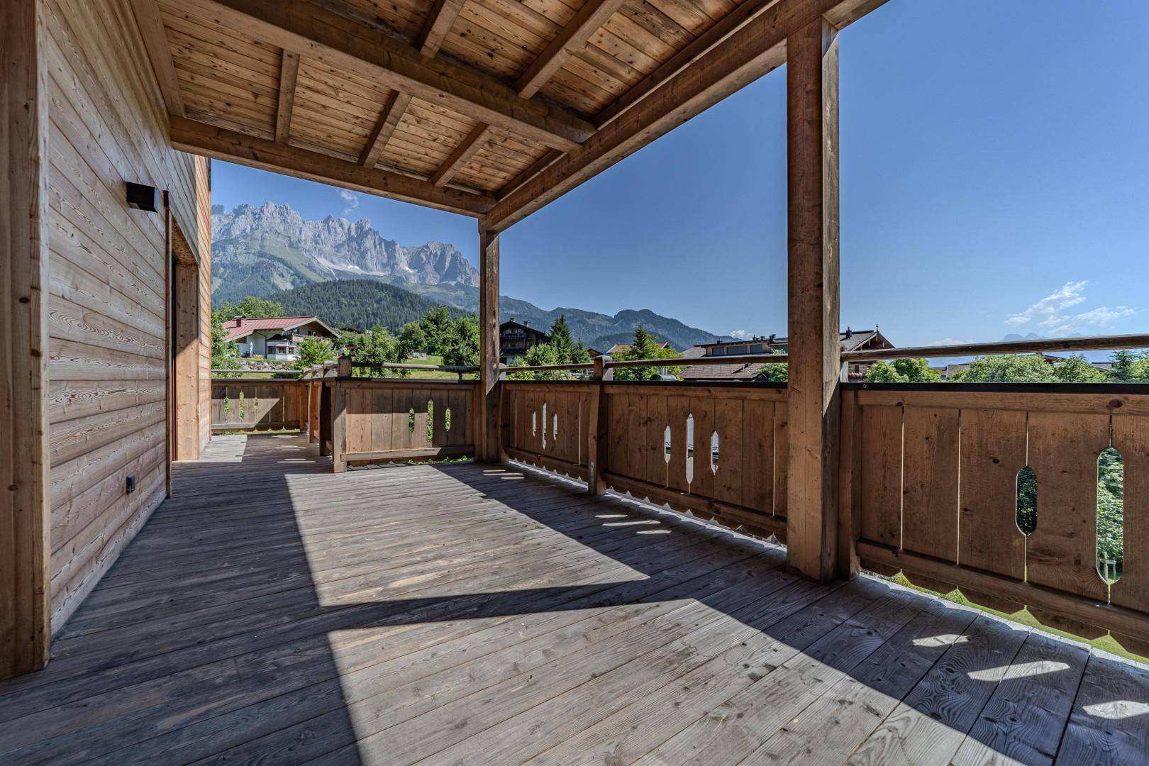 Überdachter Holzbalkon mit traditionellem Geländer und beeindruckendem Bergblick.