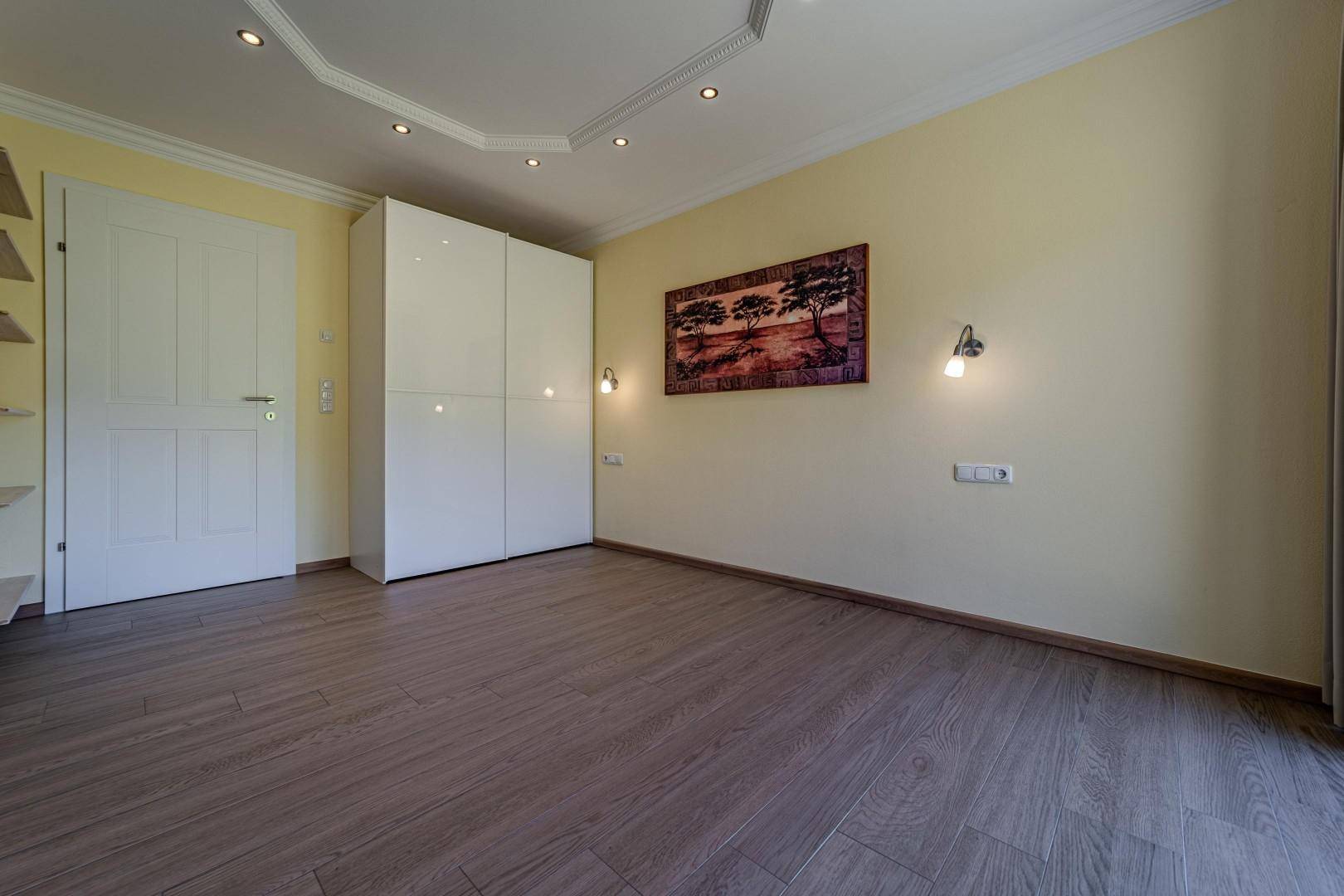 Geräumiges Schlafzimmer mit Holzboden, Einbauschrank und großen Fenstern.