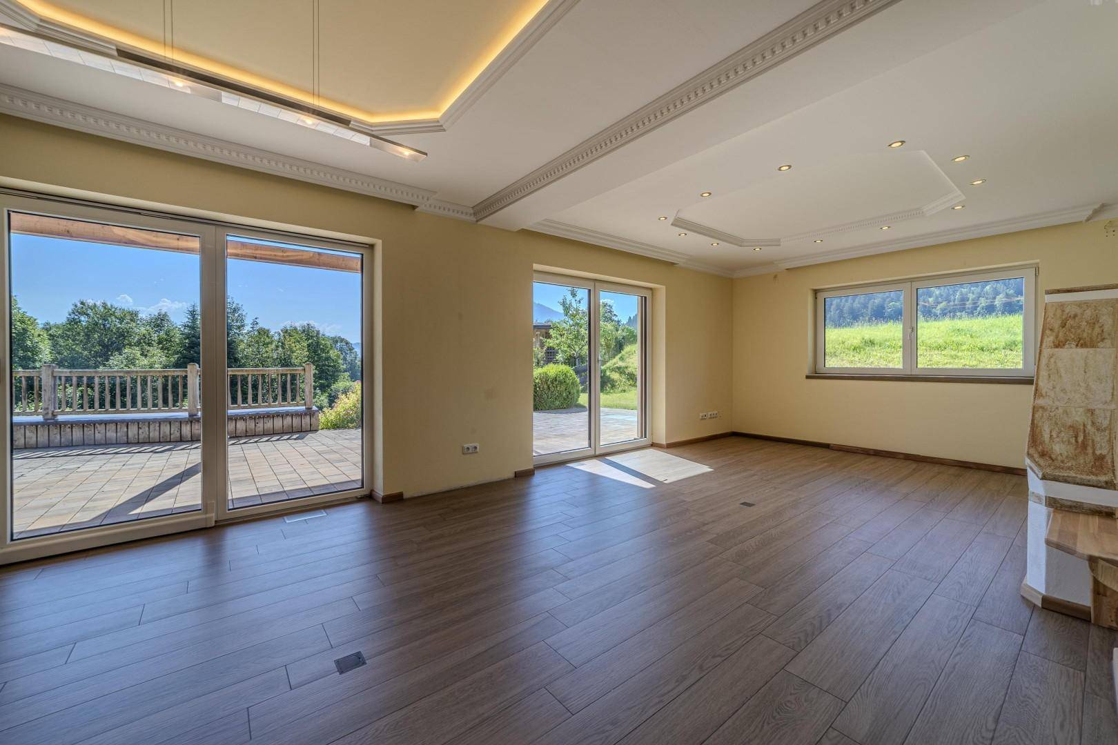Geräumiges Wohnzimmer mit Holzboden, großen Fenstern und Zugang zur Terrasse.