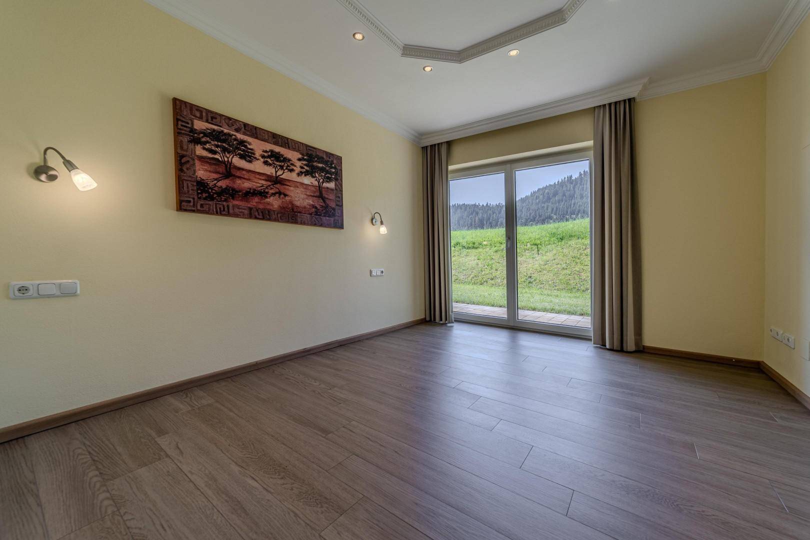 Helles Schlafzimmer mit Holzboden und direktem Zugang zur grünen Außenfläche.