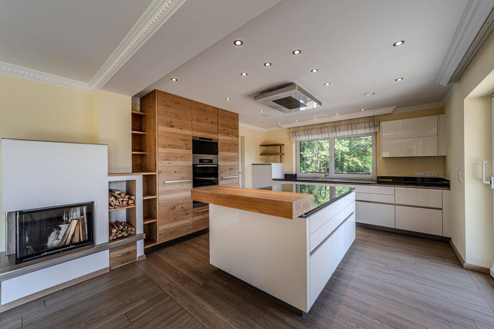 Moderne offene Küche mit Kochinsel, Holzelementen und integriertem Kamin.