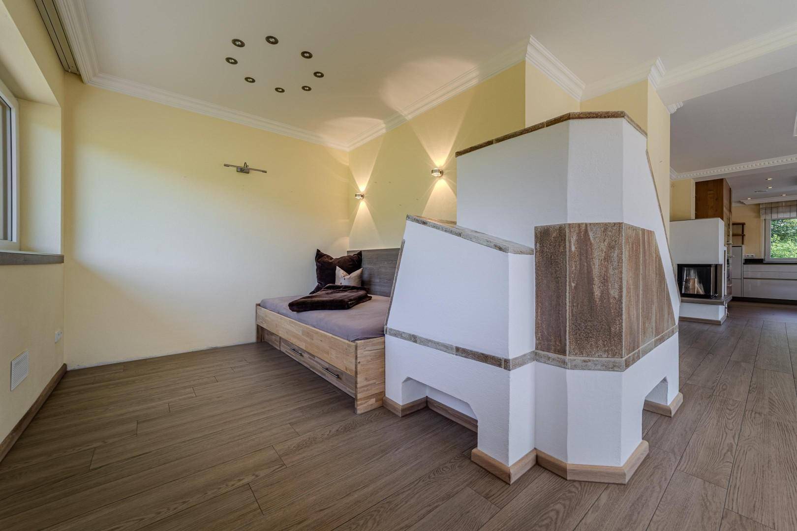 Gemütlicher Wohnbereich mit Holzboden, eingebauter Sitzbank und traditionellem Kachelofen.