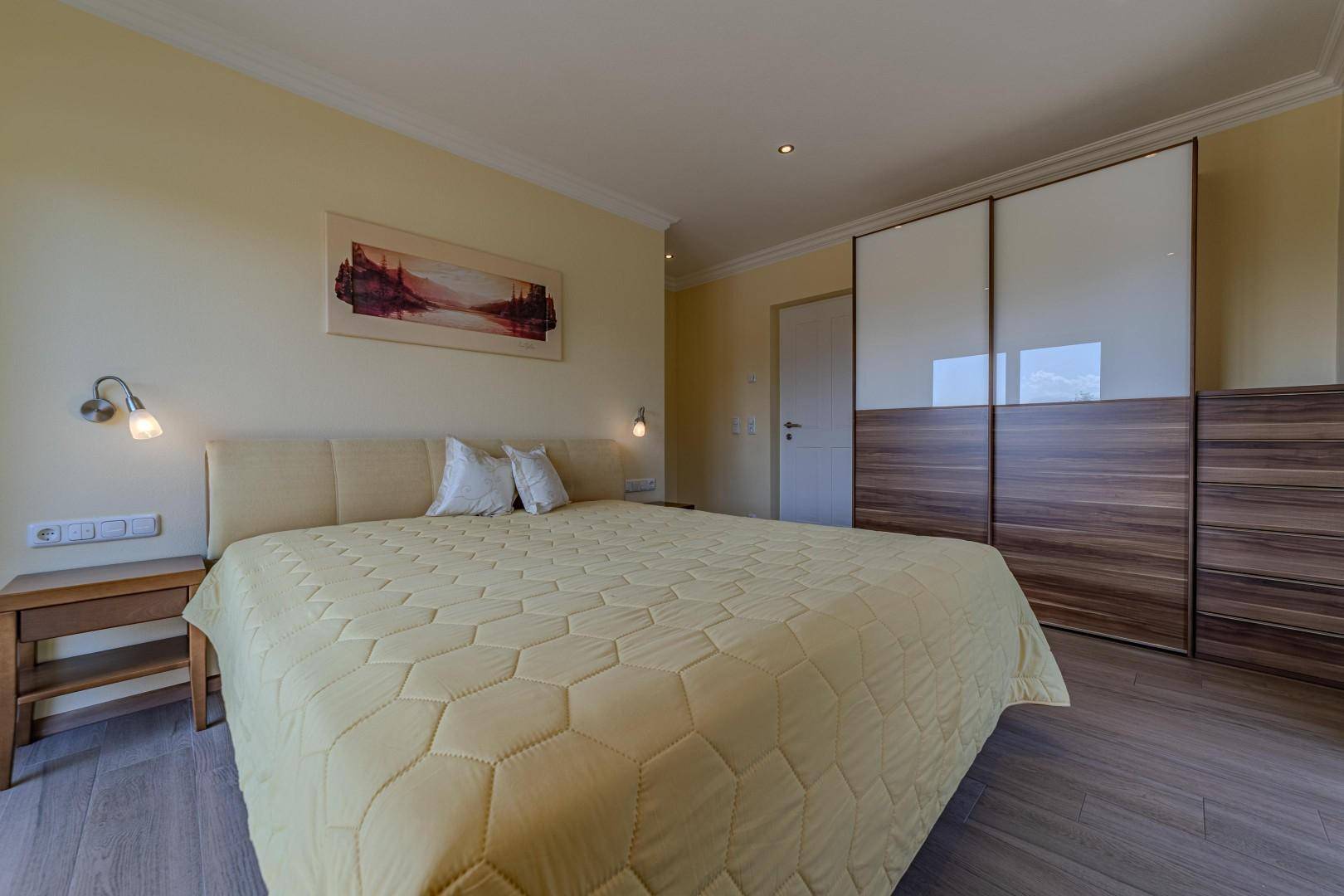 Geräumiges Schlafzimmer mit Doppelbett, Einbauschrank und Holzboden.