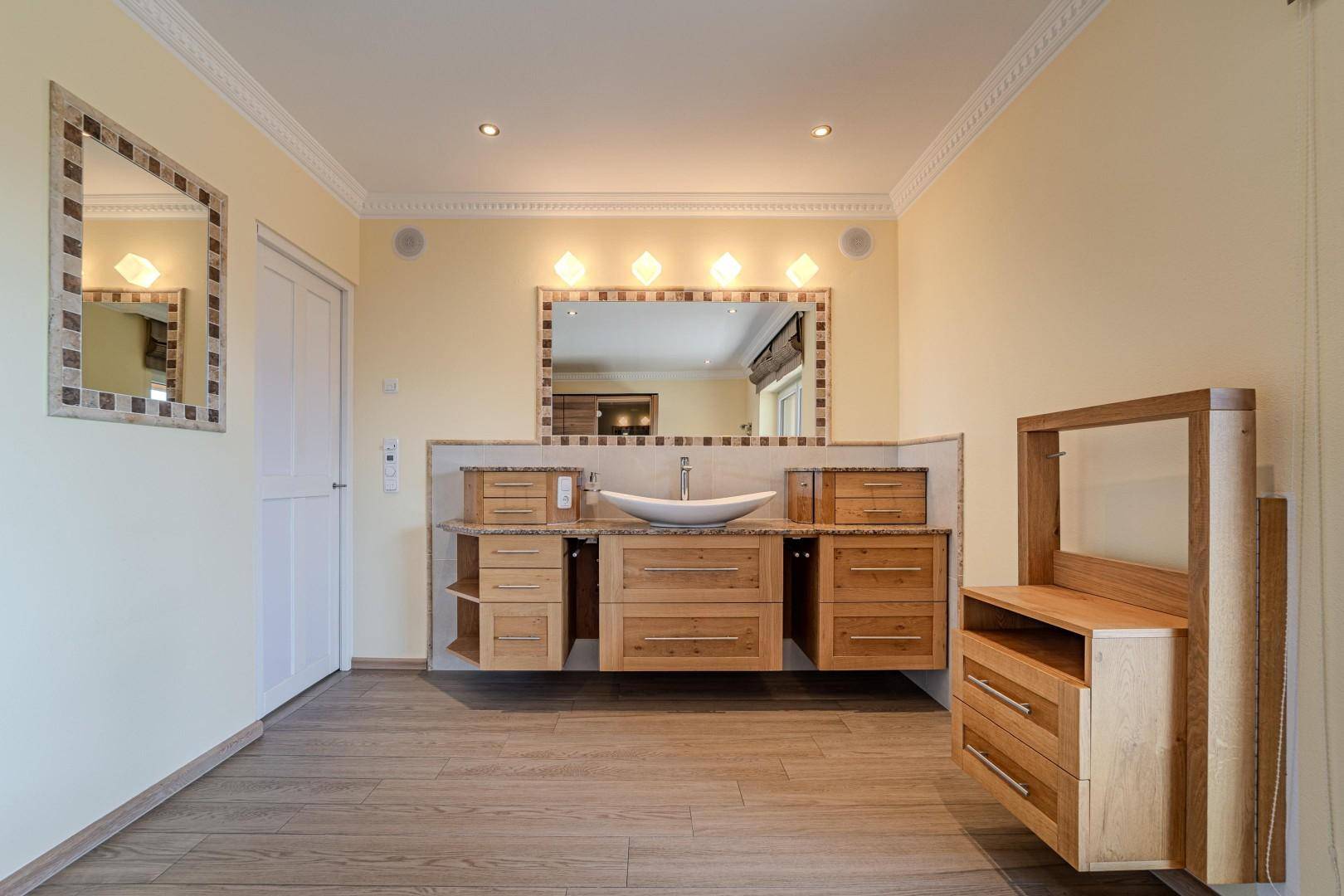 Elegantes Badezimmer mit Doppelwaschtisch, großem Spiegel und Holzschränken in modernem Design.
