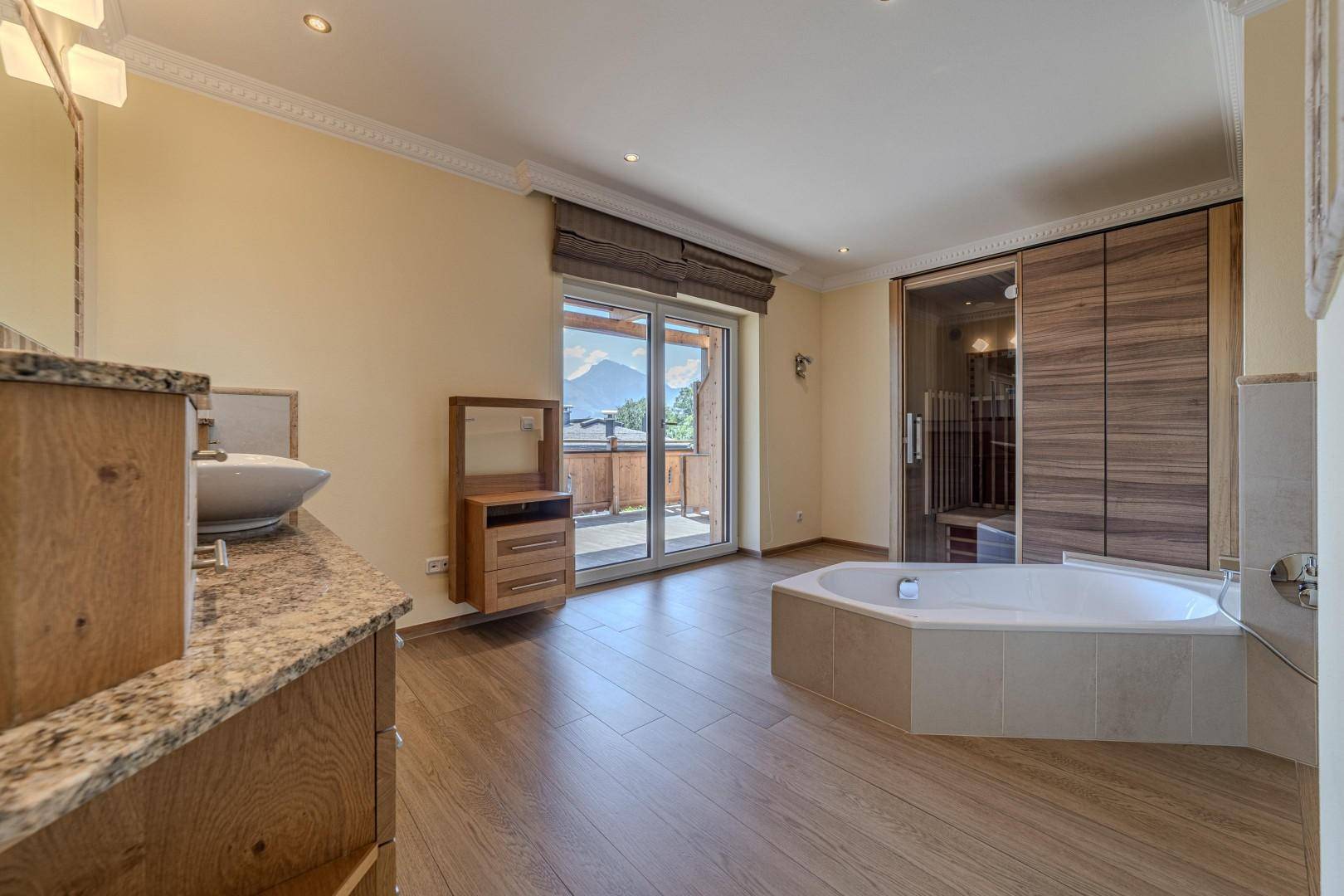 Großes Badezimmer mit Badewanne, Granitwaschtisch und integrierter Sauna.