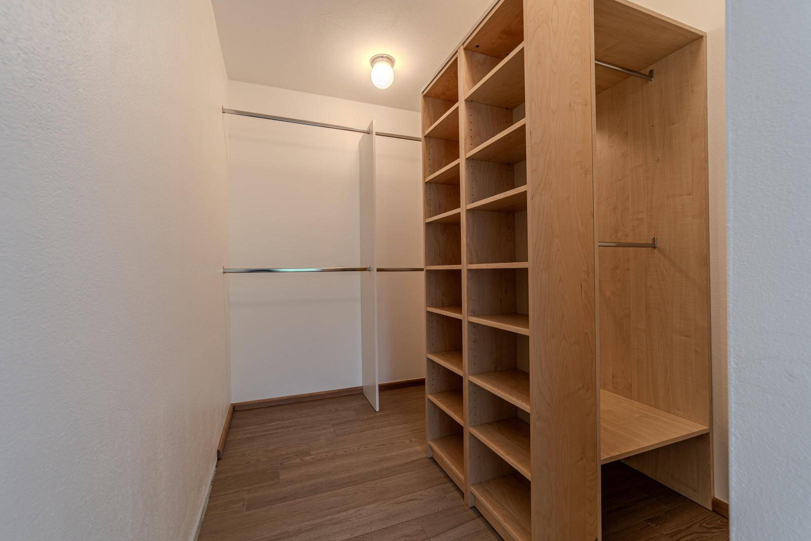 Geräumiger begehbarer Kleiderschrank mit Regalen und Kleiderstangen.