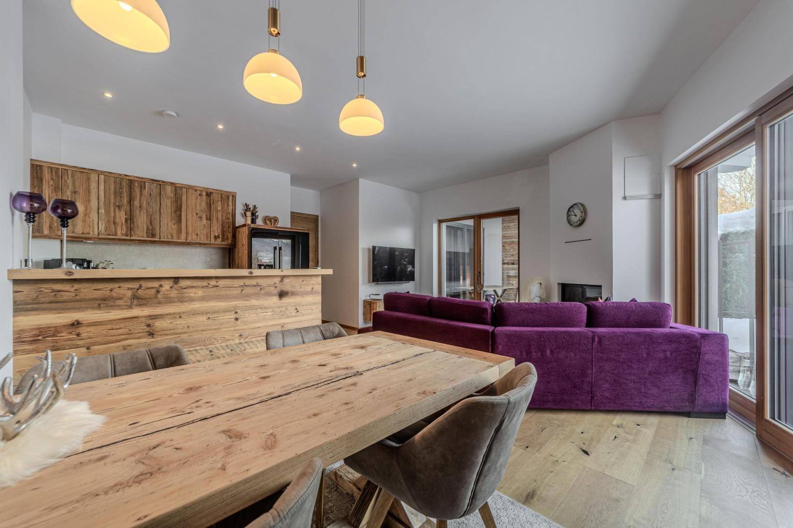 Geräumiger Essbereich mit Holztisch und offener Küche in modernem alpinen Stil.