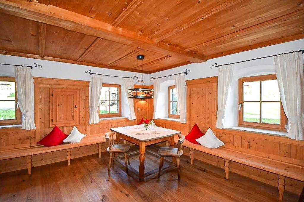 Heller Essbereich mit Holzboden, traditionellen Holzbänken und Blick ins Grüne.