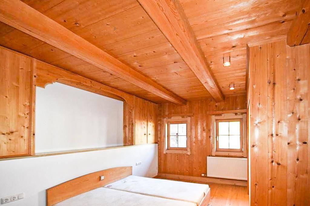 Schlafzimmer mit Holzbalkendecke, Holzboden und traditionellen Holzelementen.
