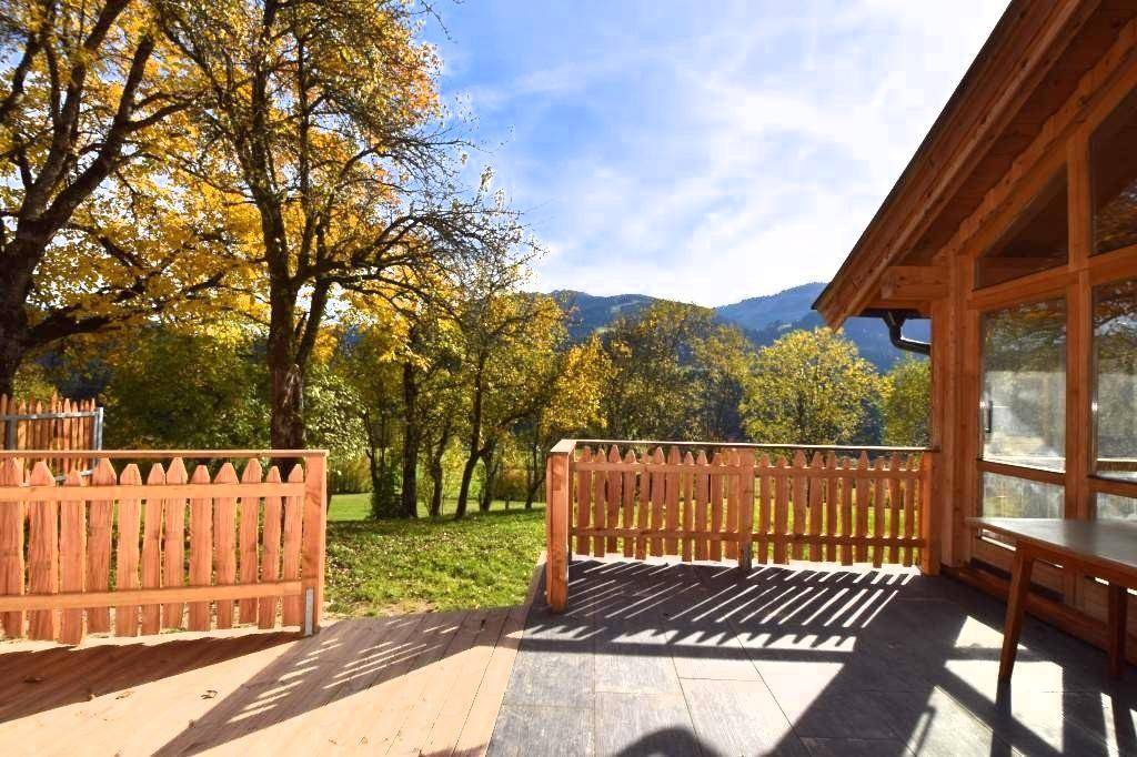 Große Holzterrasse mit Zaun und weitem Blick auf die grüne Landschaft und Berge.