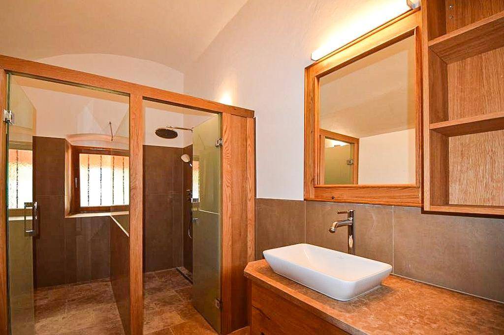 Modernes Badezimmer mit begehbarer Dusche, Einzelwaschbecken und Holzdetails.