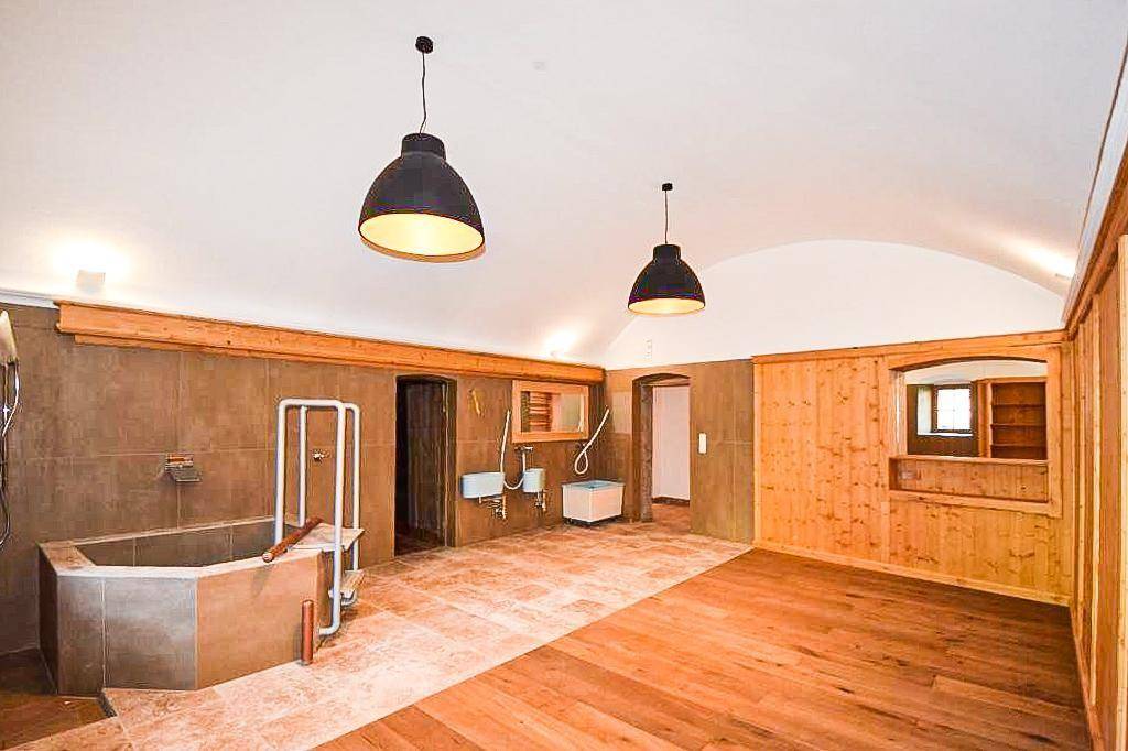 Geräumiges Badezimmer mit großer Badewanne, Holzboden und gewölbter Decke.
