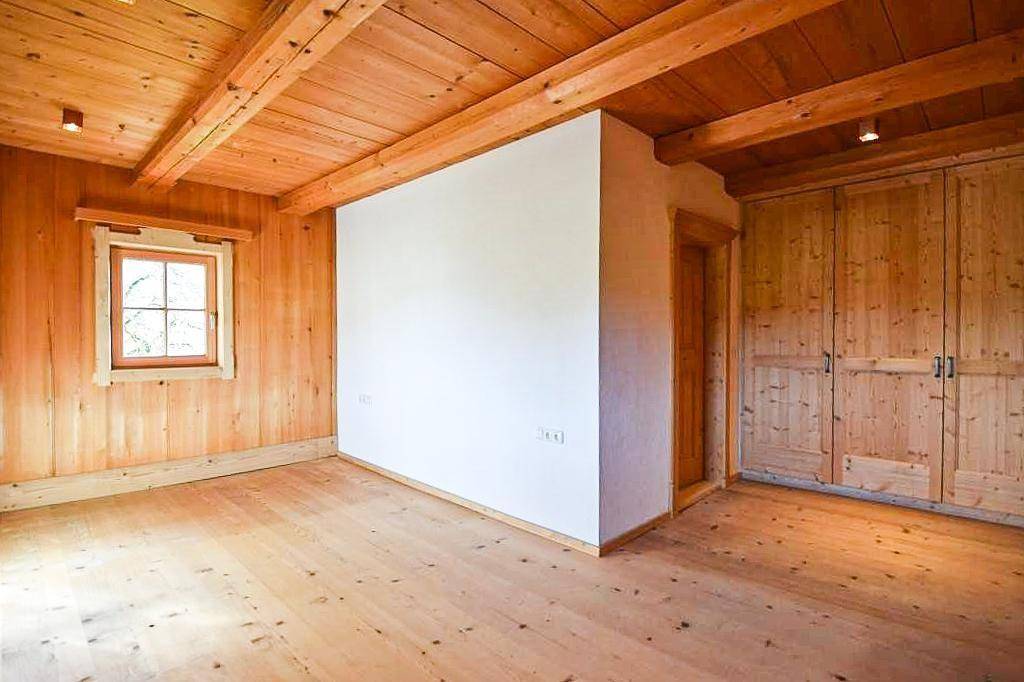 Geräumiges Schlafzimmer mit Holzboden, Holzbalkendecke und Einbauschränken.