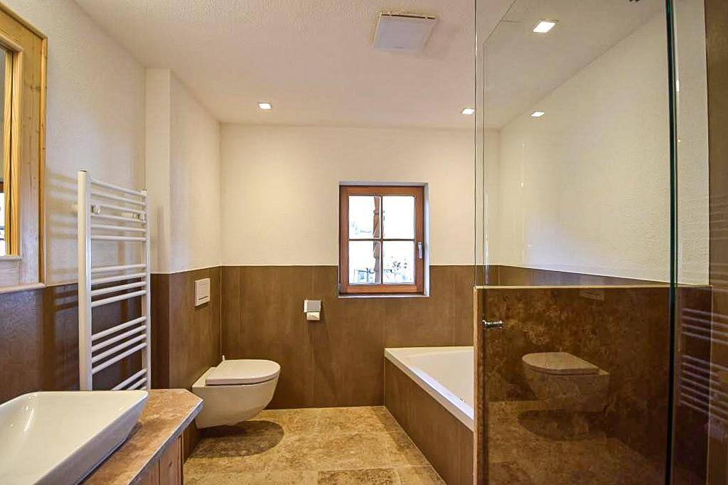 Helles Badezimmer mit Badewanne, Dusche, WC und beheiztem Handtuchhalter.