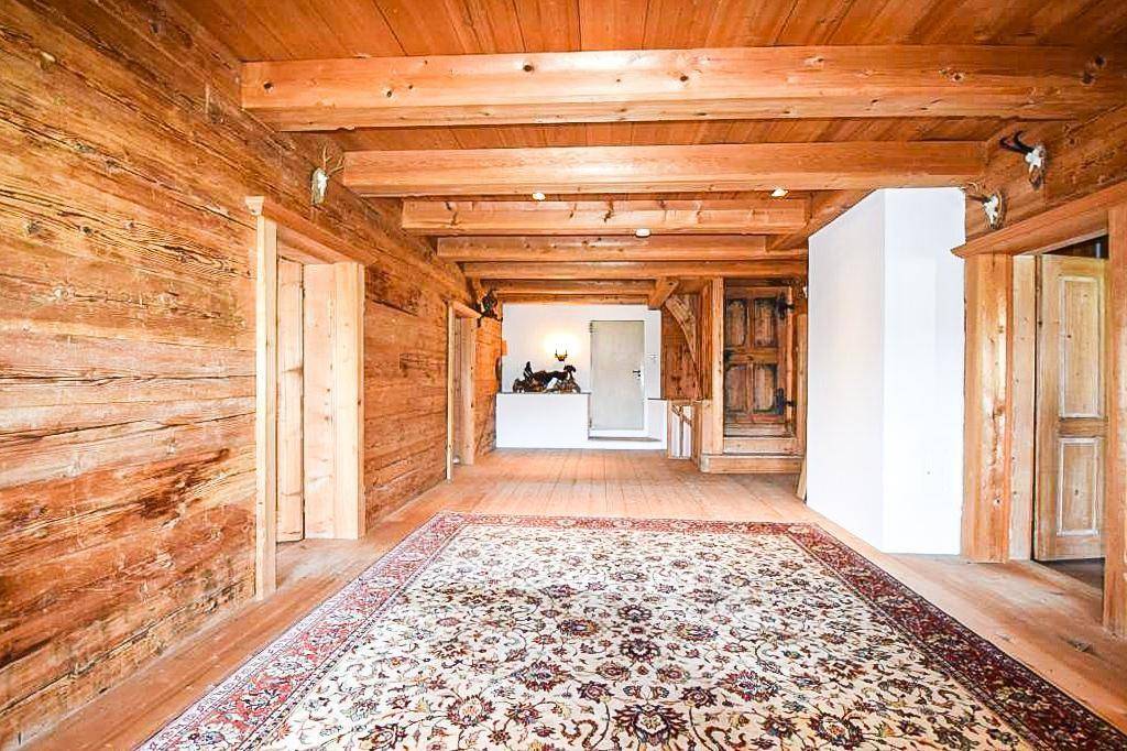 Geräumiger Flur mit Holzbalkendecke, Holzboden und traditionellem Teppich.