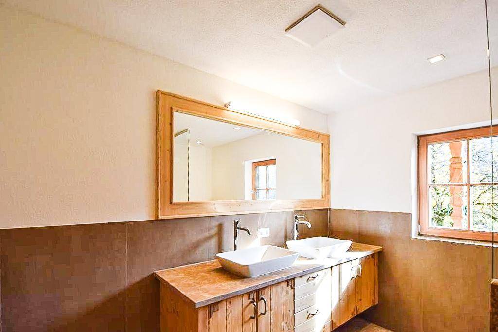 Modernes Badezimmer mit Doppelwaschbecken, Holzunterschrank und großem Spiegel.