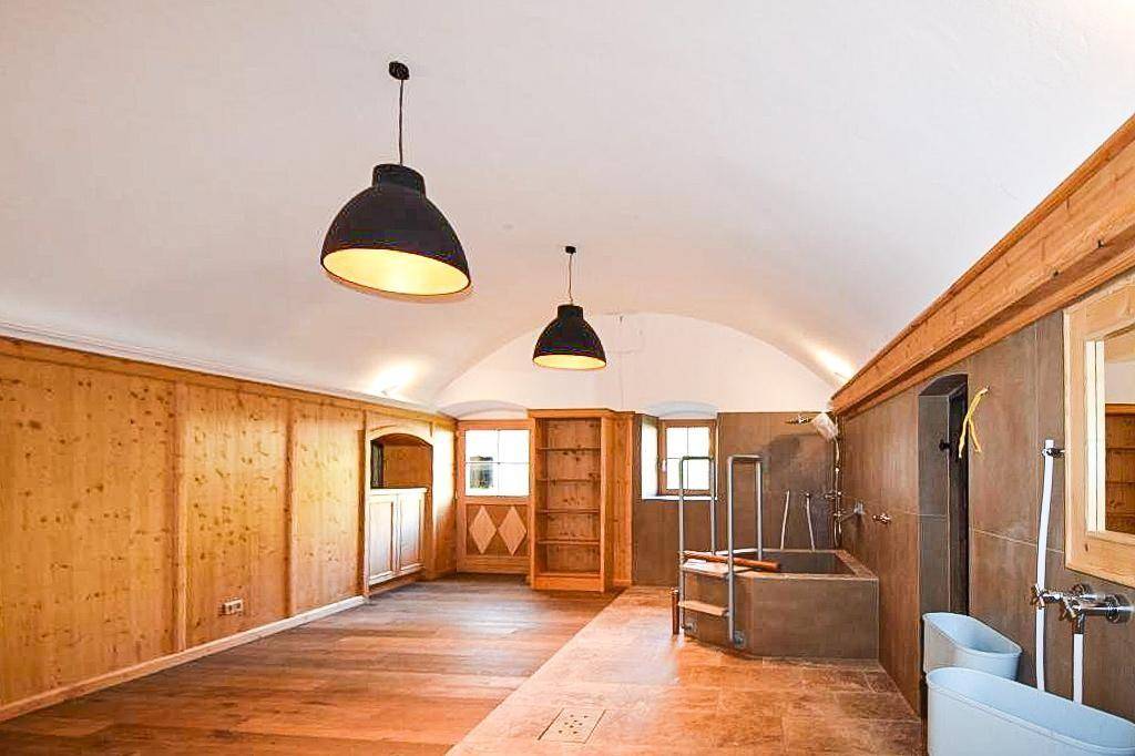 Großes Badezimmer mit Badewanne, Holzboden und traditionellen Holzelementen.