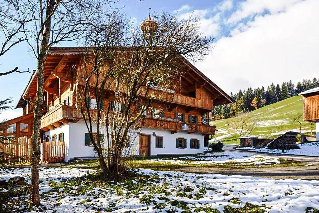 Traditionelles Holzhaus im Alpenstil mit Balkonen und schneebedecktem Vorgarten.
