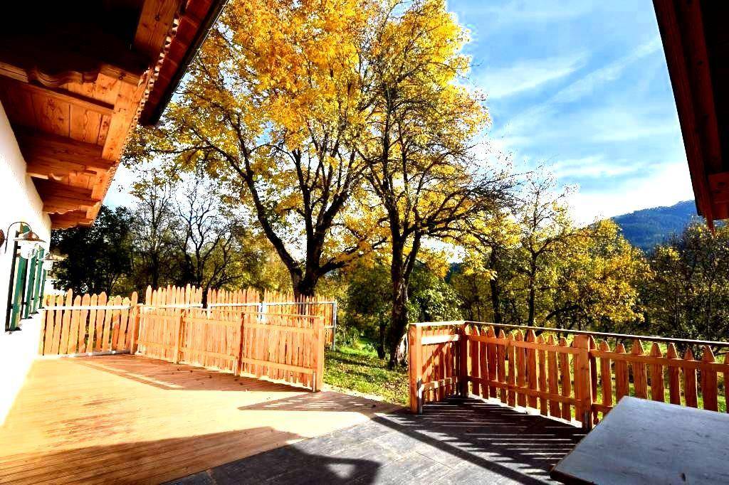 Sonniger Außenbereich mit Holzterrasse, Zaun und Blick auf die umliegende Natur.