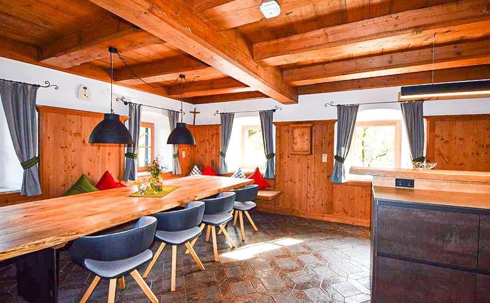 Gemütlicher Essbereich mit Holztisch, Holzbalkendecke und traditioneller Holzvertäfelung an den Wänden.