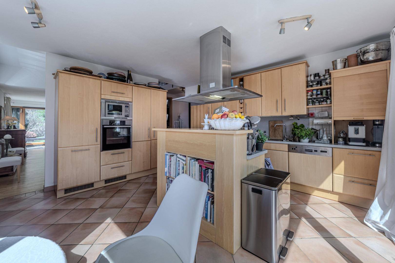 Moderne Holzküche mit Einbaugeräten, Kochinsel und viel Stauraum.
