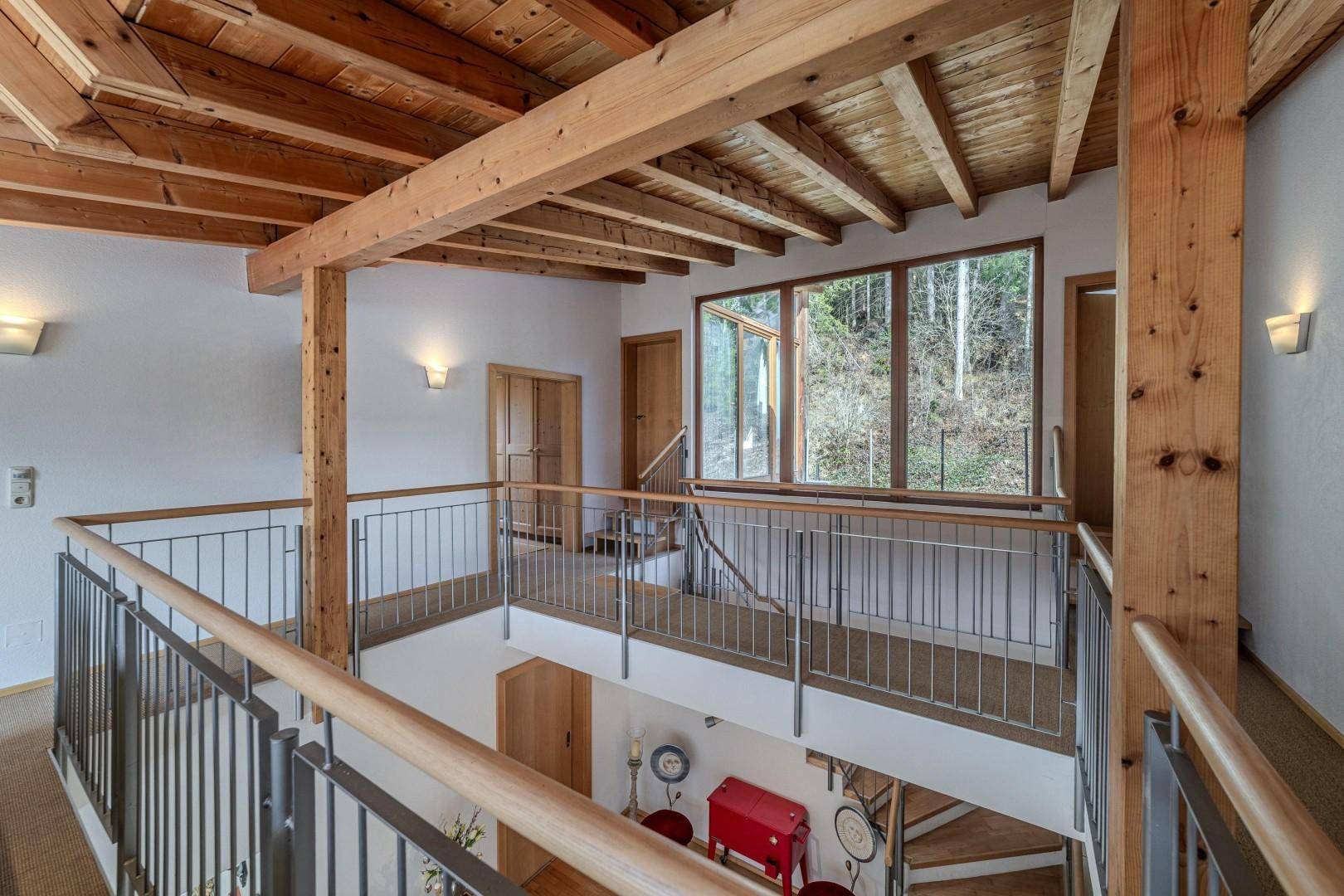 Heller Flur im Obergeschoss mit Holzdecke, Galerie und großen Fenstern.