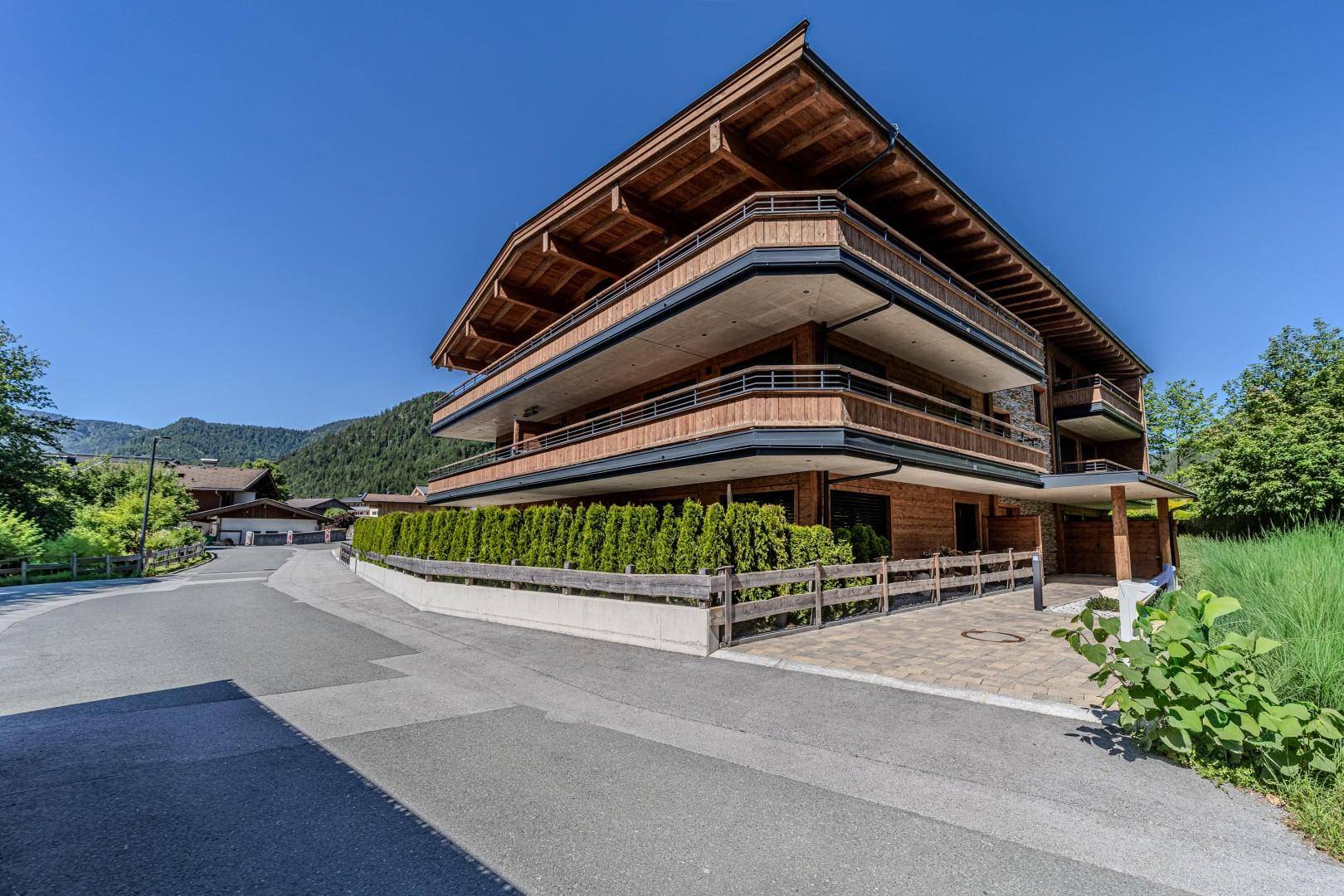 Elegantes Gebäude mit Holzverkleidung und weitläufigen Balkonen, harmonisch in die Bergwelt integriert.