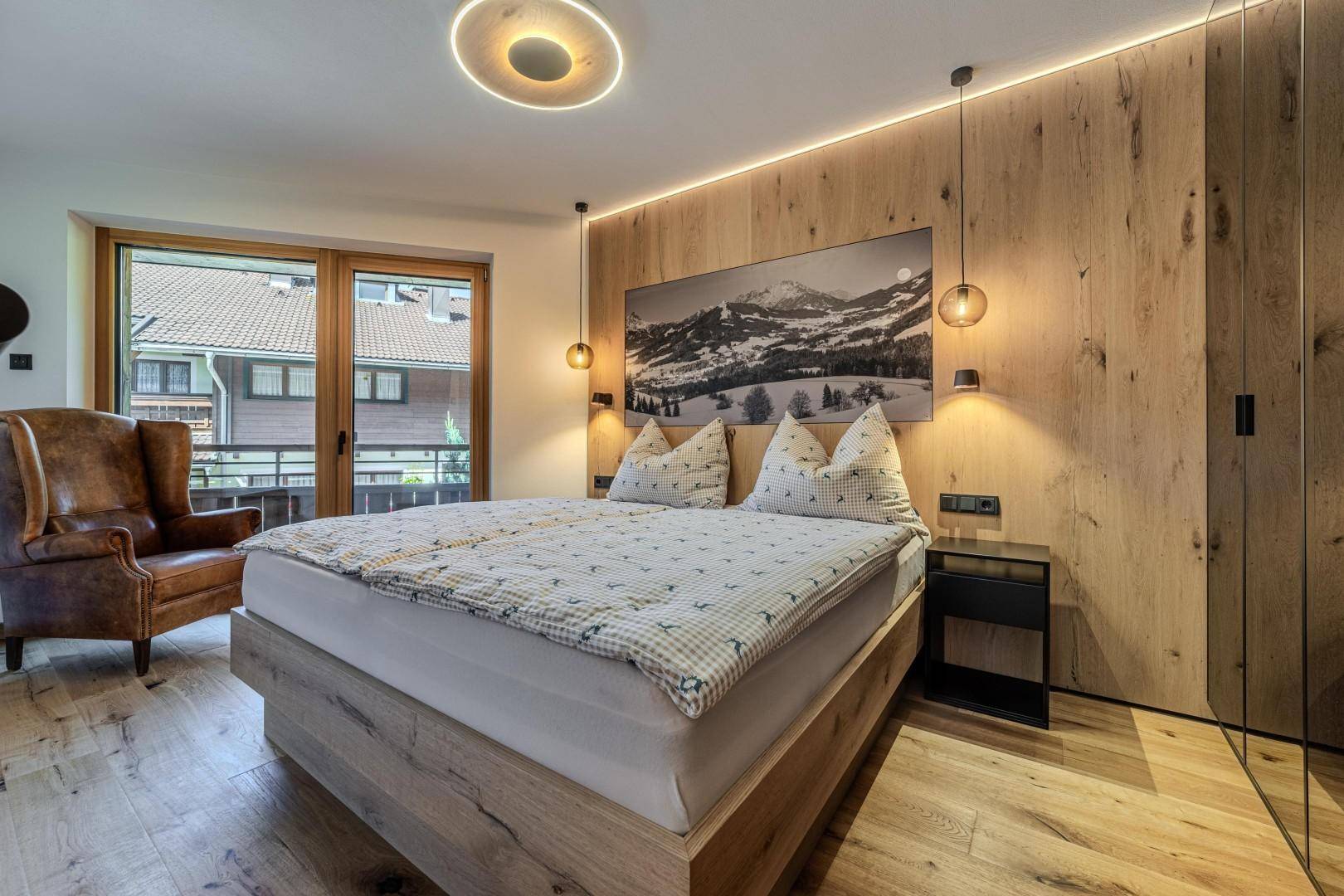 Modernes Schlafzimmer mit Holzwand, Doppelbett und großem Wandbild über dem Bett.