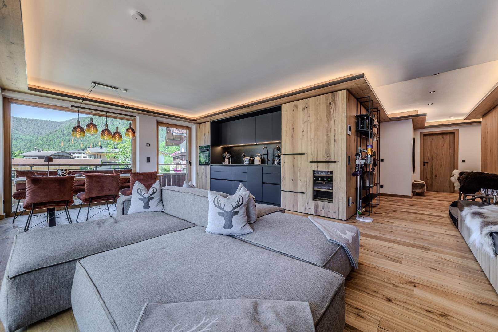 Offener Wohnbereich mit integrierter Küche, Holzelementen und gemütlichem Sofa.
