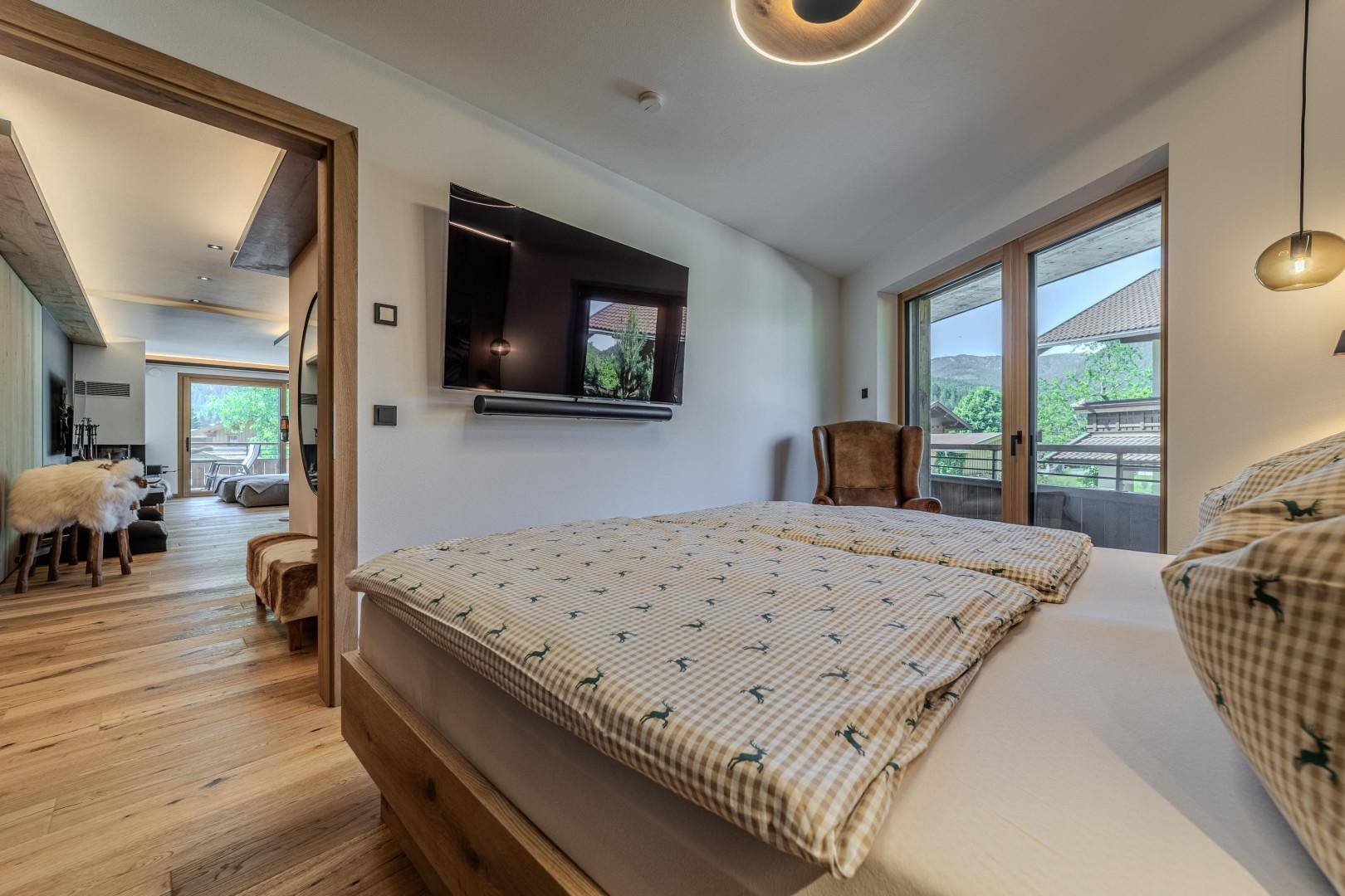 Schlafzimmer mit Holzboden, Fernseher und Blick auf den Wohnbereich.